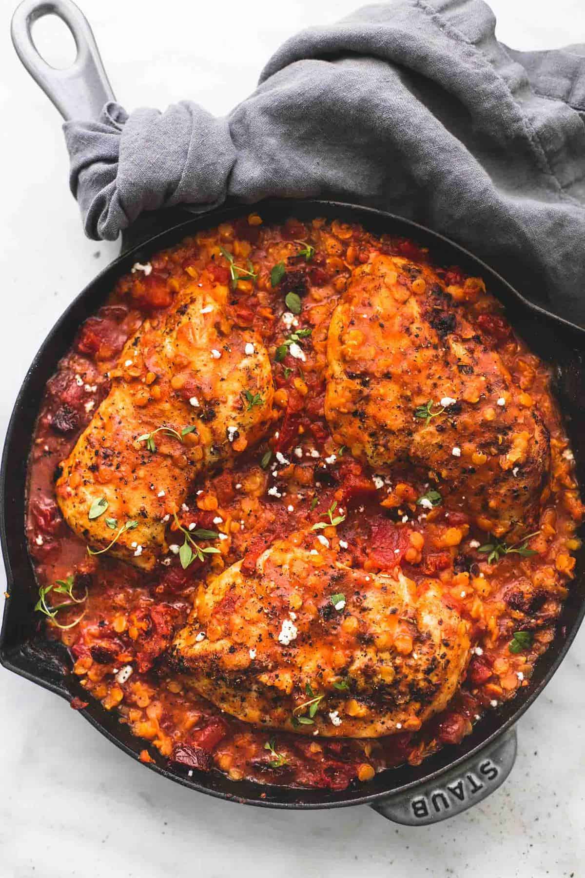 top view of Greek sun dried tomato chicken and lentils in a pan.