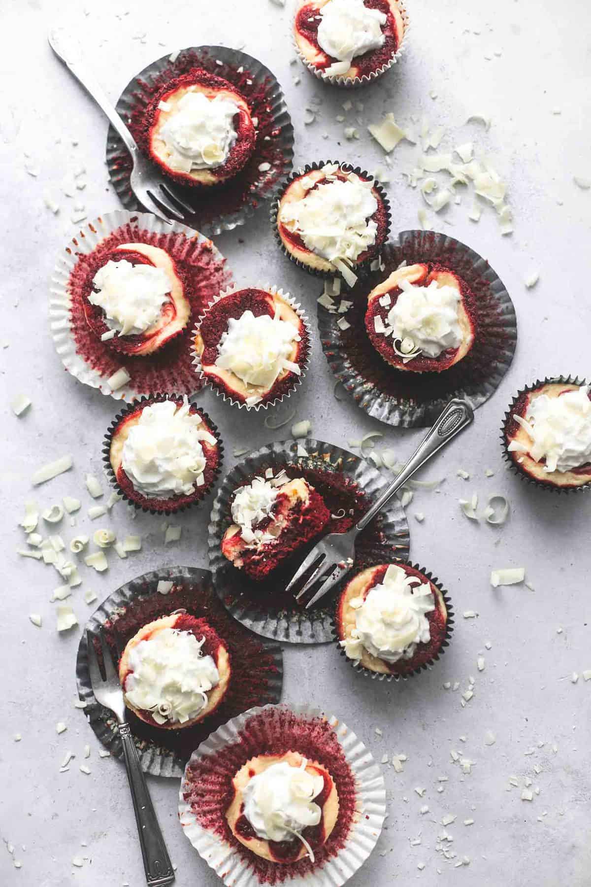 top view of red velvet cheesecake bites in and on cupcake liners with forks.