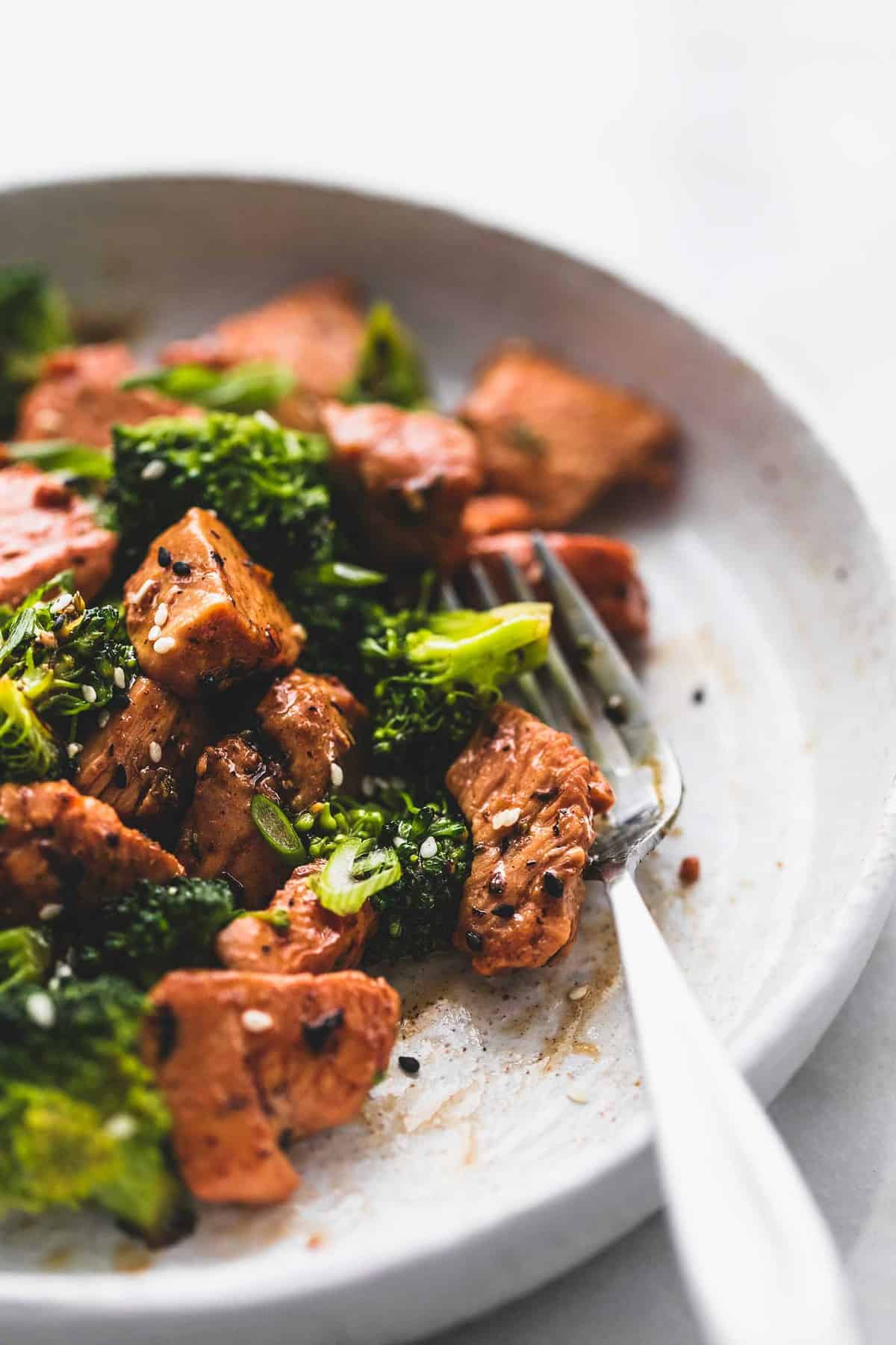 close up of chicken and broccoli stir fry with a fork on a plate.