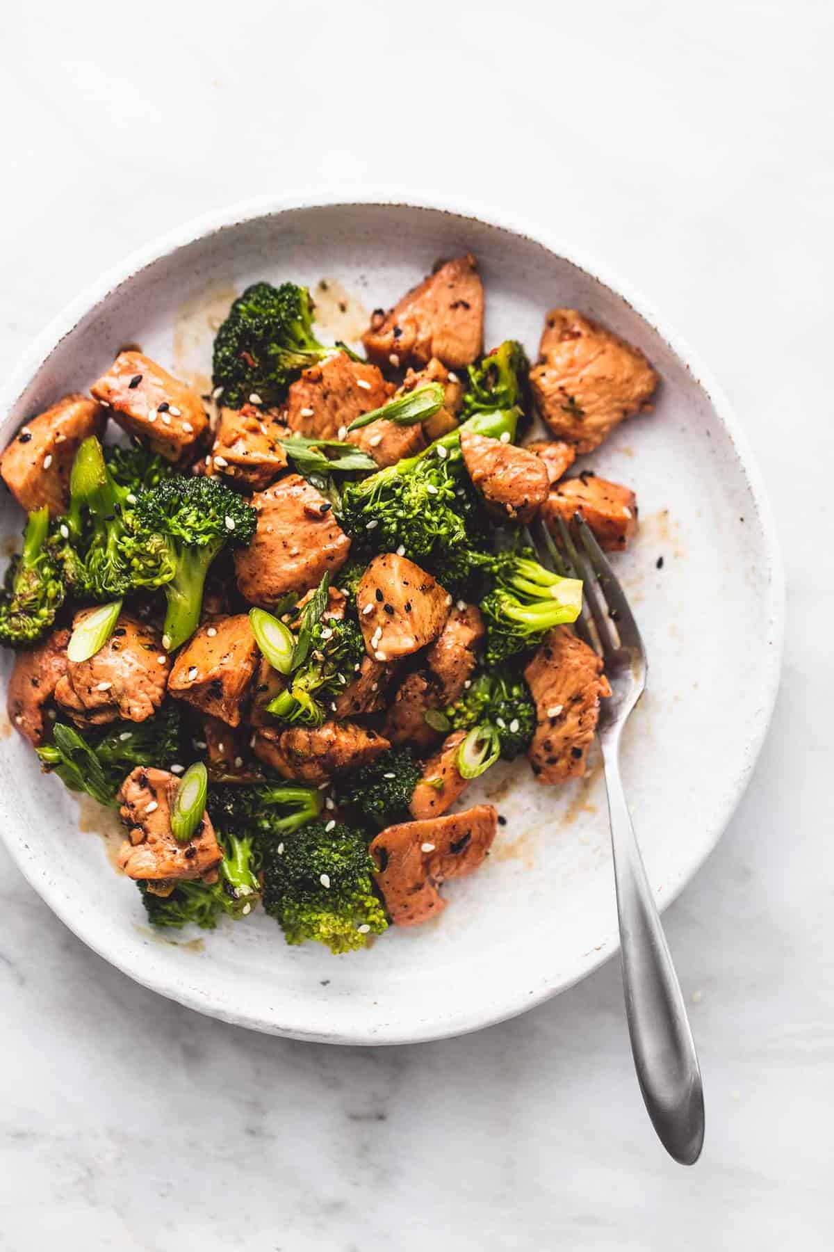 top view of chicken and broccoli stir fry with a fork on a plate.