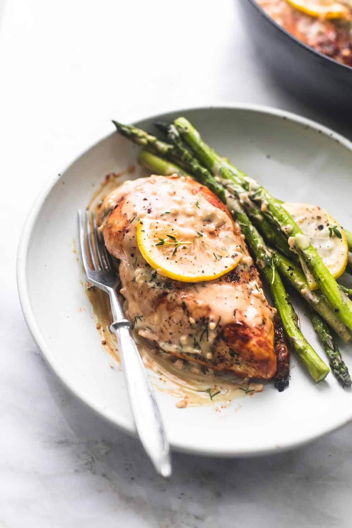 creamy lemon chicken and asparagus with a fork on a plate.