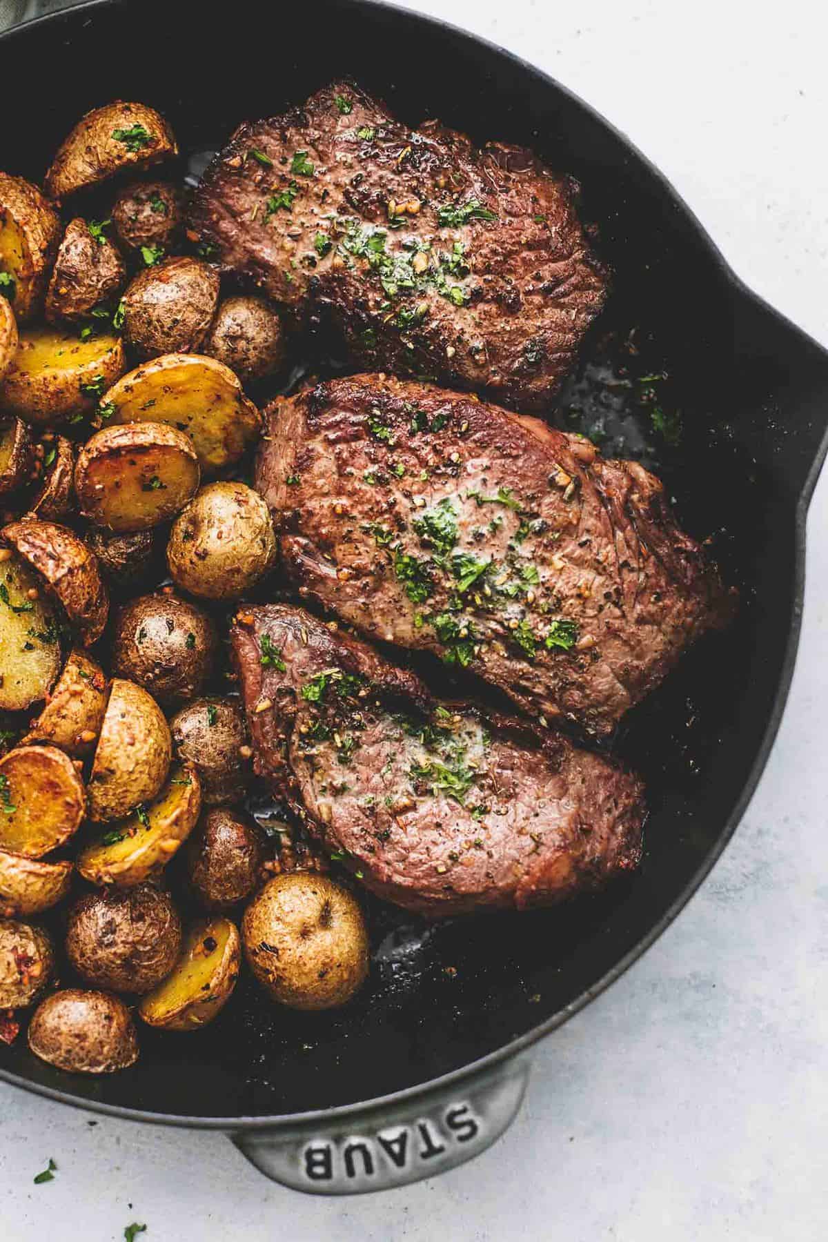 close up top view of garlic butter steak and potatoes skillet in a skillet.