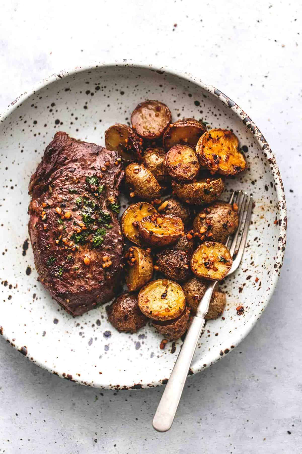 top view of garlic butter steak and potatoes skillet with a fork on a plate.