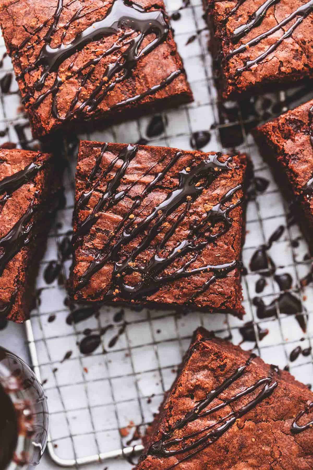 close up top view of brownies drizzled with hot fudge on a cooling rack.