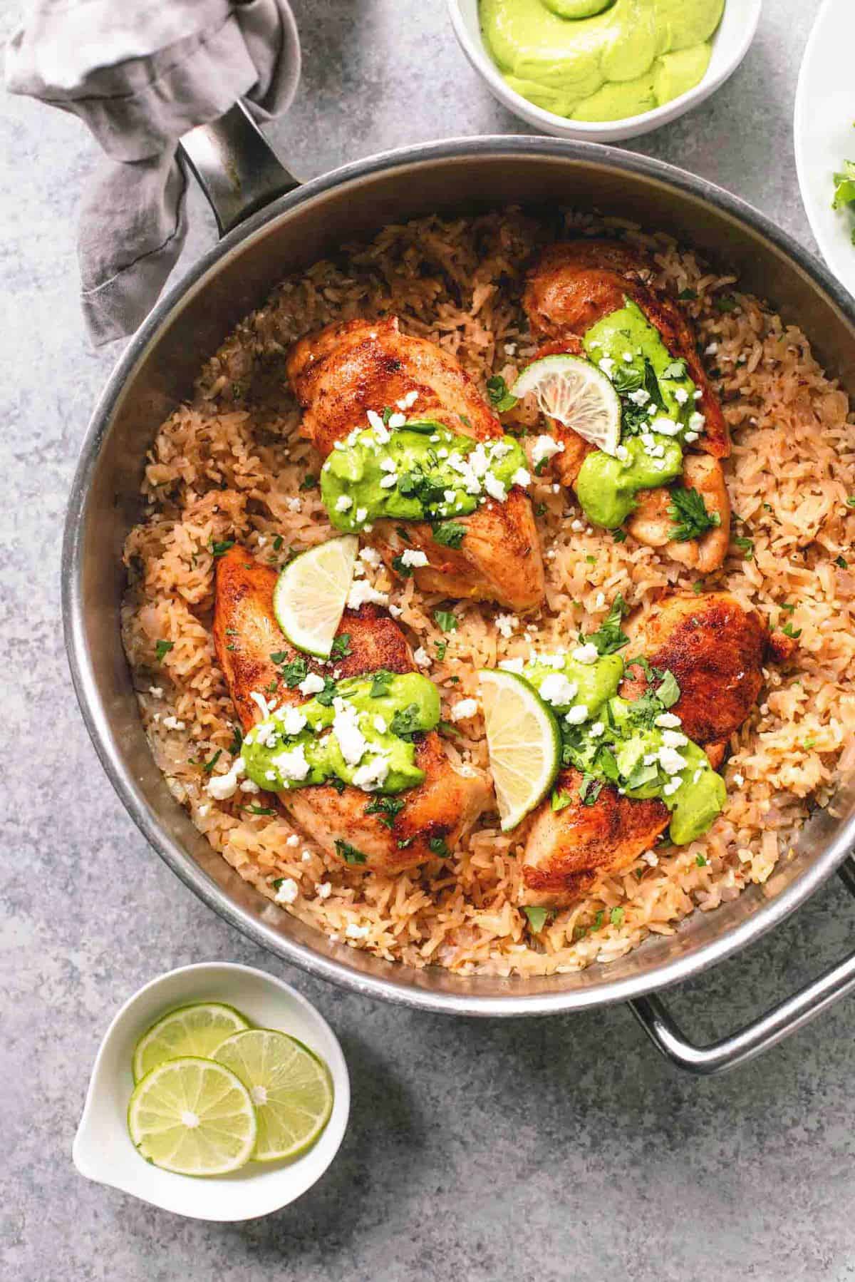 top view of one pan creamy cilantro lime chicken and rice in a pan with lime slices in bowl on the side.