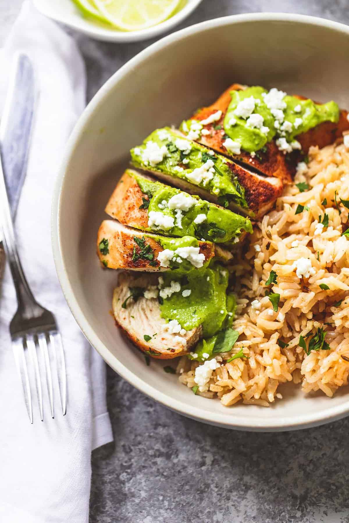 close up top view of one pan creamy cilantro lime chicken and rice in a bowl with a fork on the side.