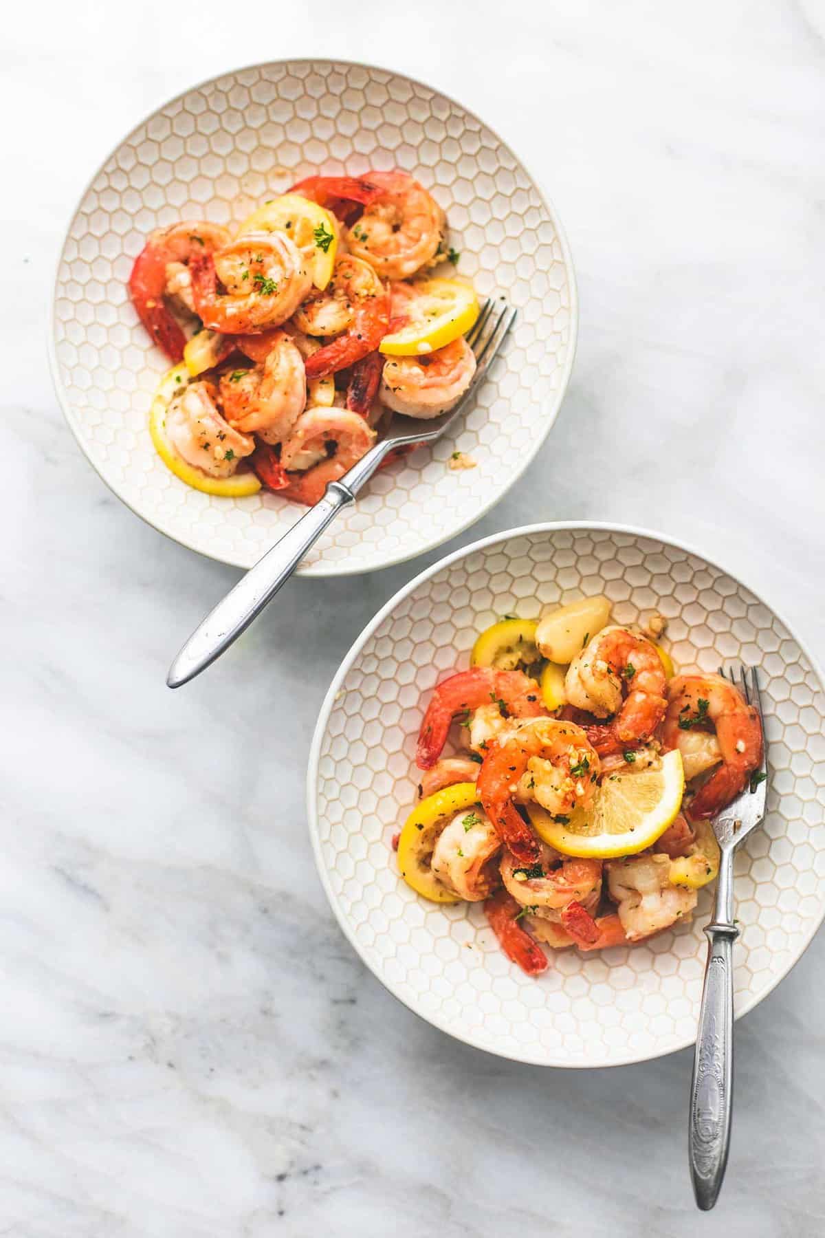 top view of two bowls with forks and lemon garlic butter shrimp in them.