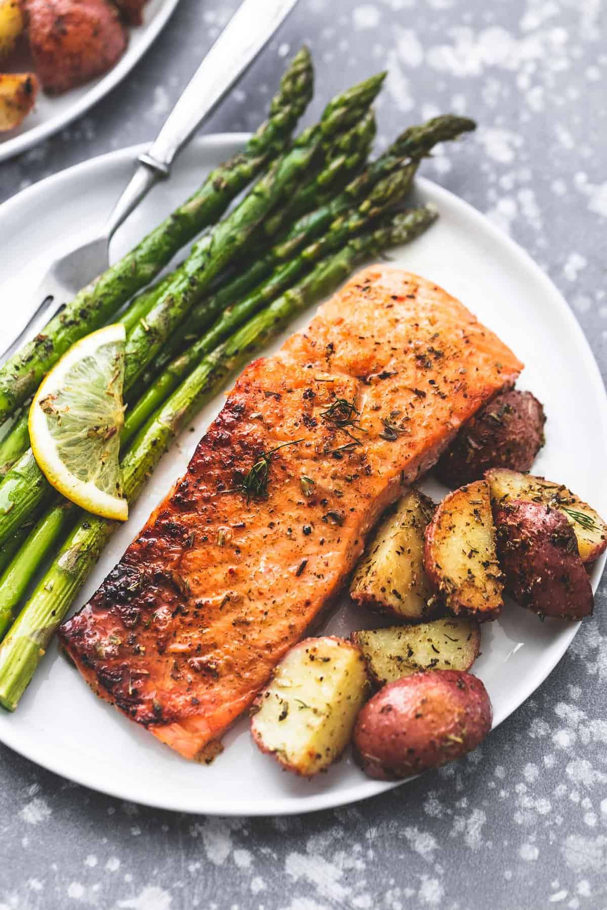 sheet pan baked salmon and asparagus with potatoes and a fork on a plate.