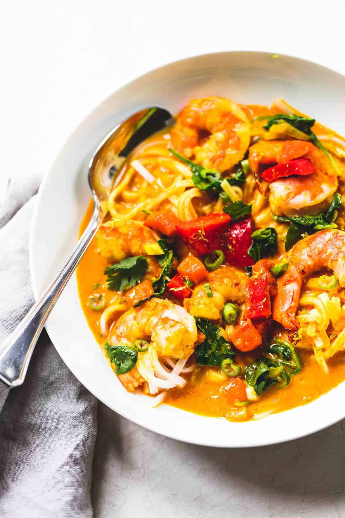 close up top view of Thai coconut curry with a spoon in a bowl.