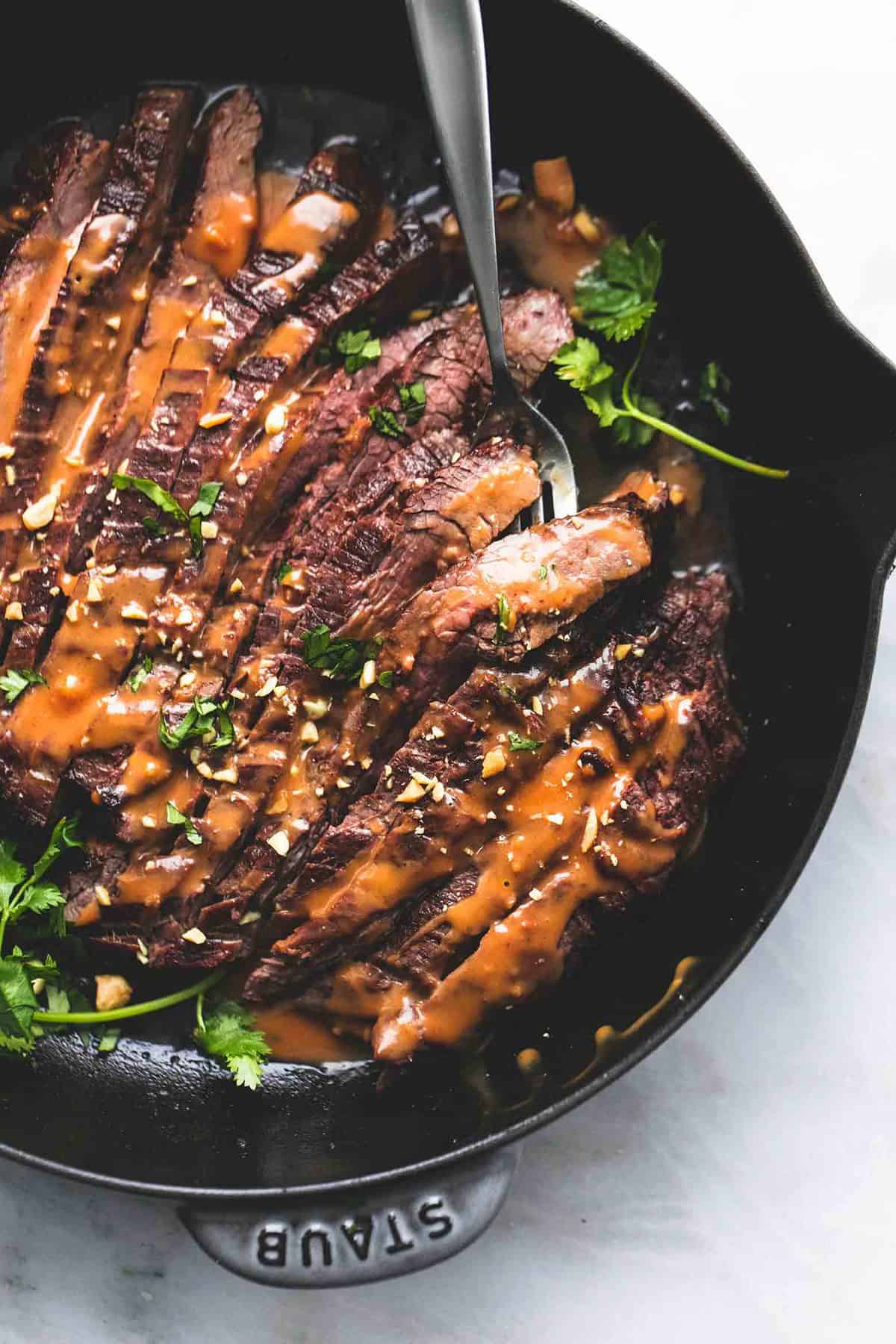 close up top view of Thai peanut beef with a fork in a pan.