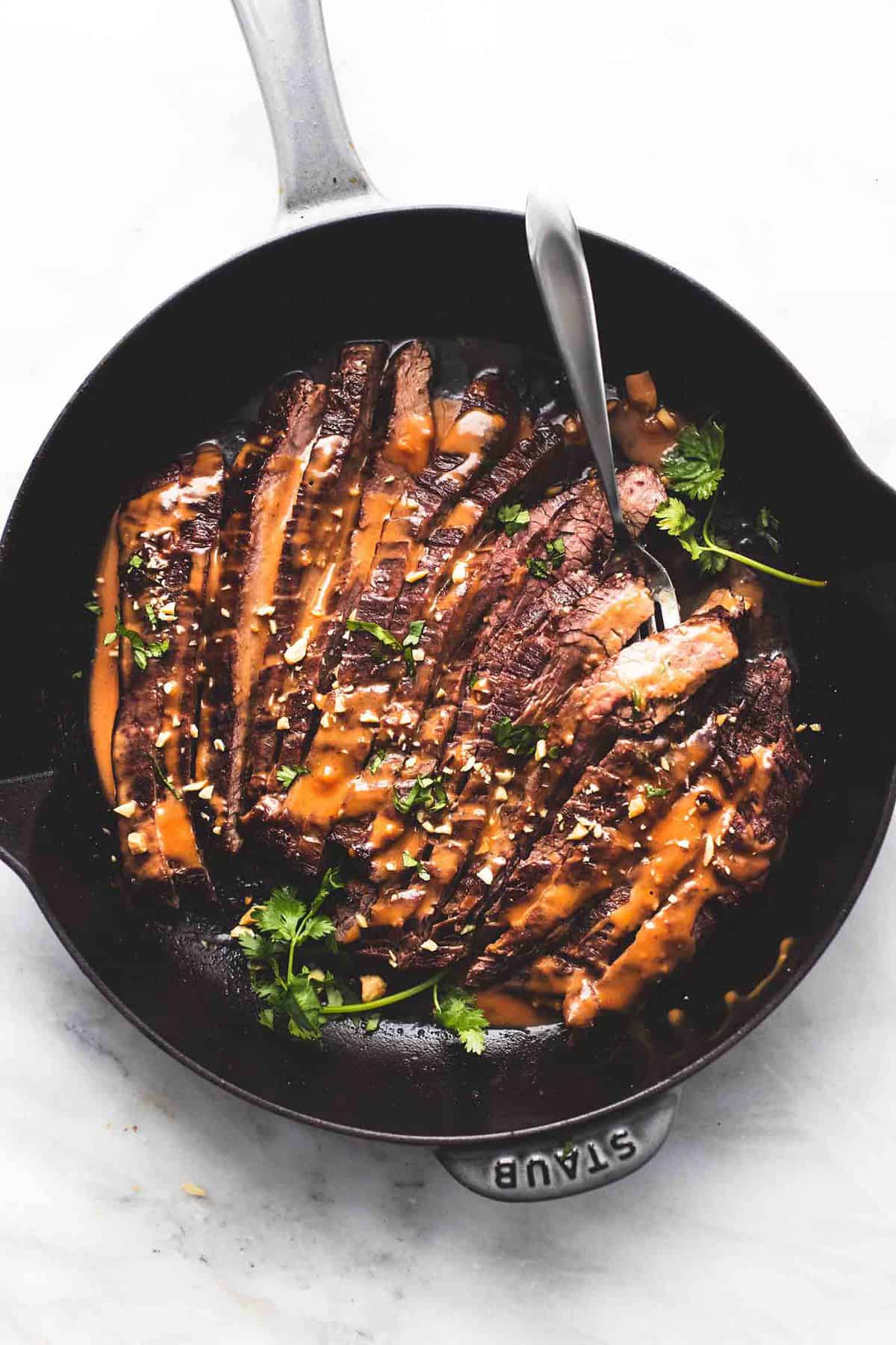 top view of Thai peanut beef with a fork in a pan.