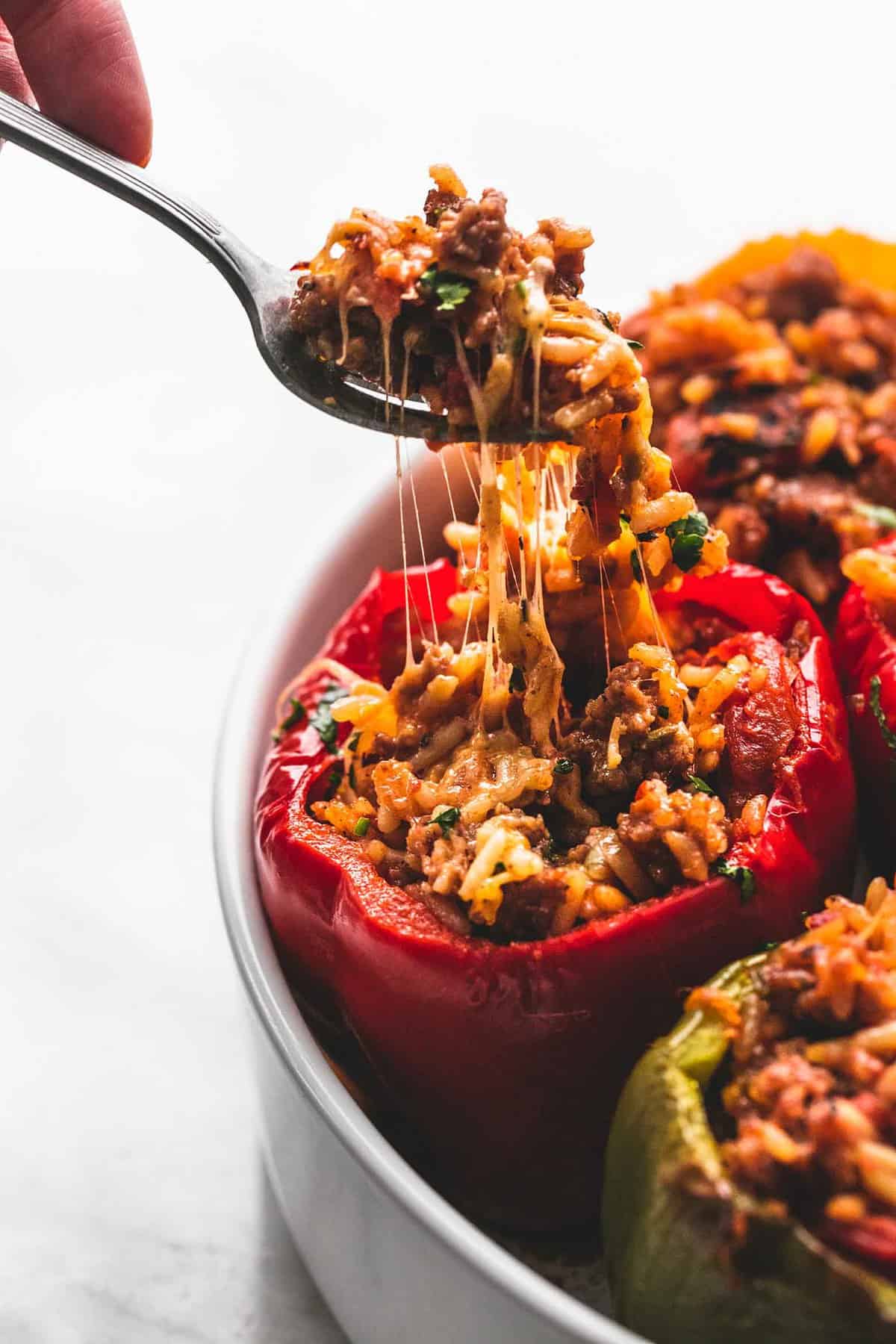a spoon with a bite of stuffed peppers being lifted from a stuffed pepper.