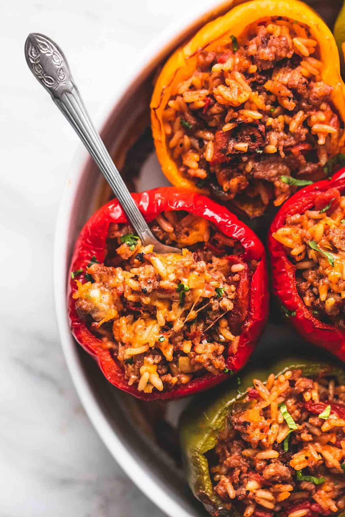 close up top view of stuffed peppers with a spoon in one pepper on a round dish.