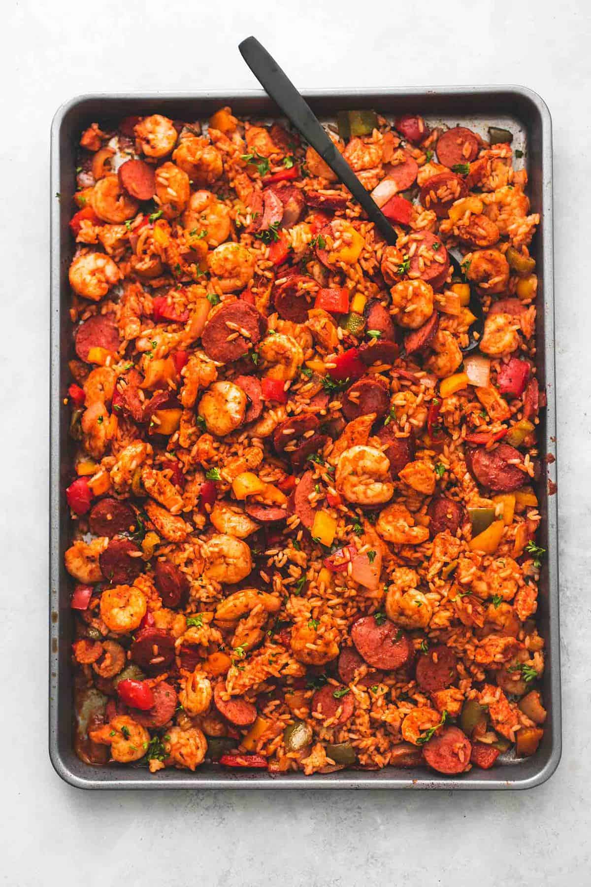 top view of sheet pan jambalaya with a serving spoon on a sheet pan.