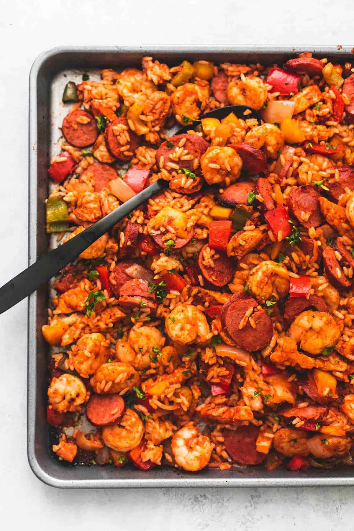 close up top view of sheet pan jambalaya with a serving soon on a sheet pan.