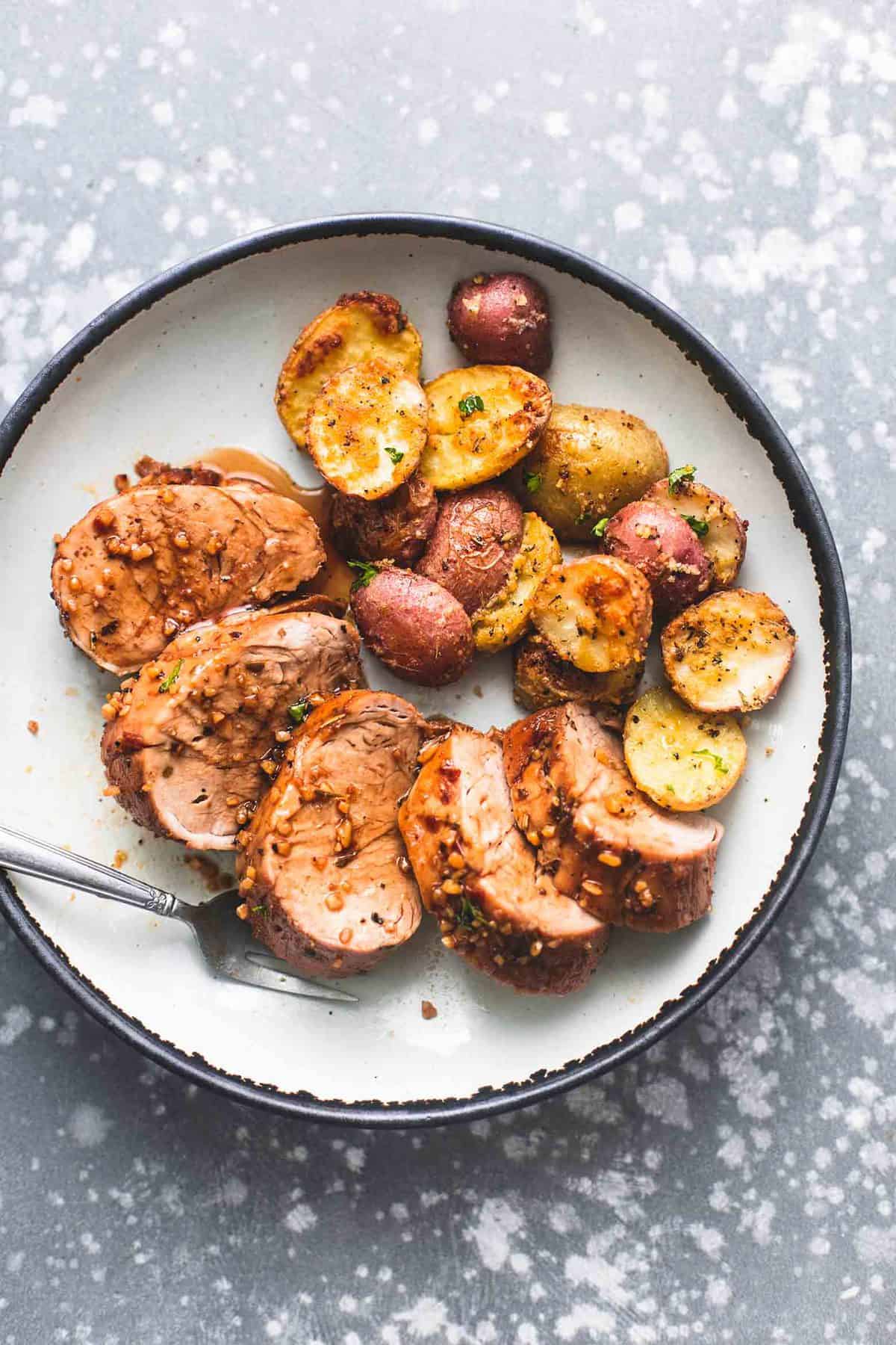 top view of sheet pan pork tenderloin and potatoes with a fork on a plate.