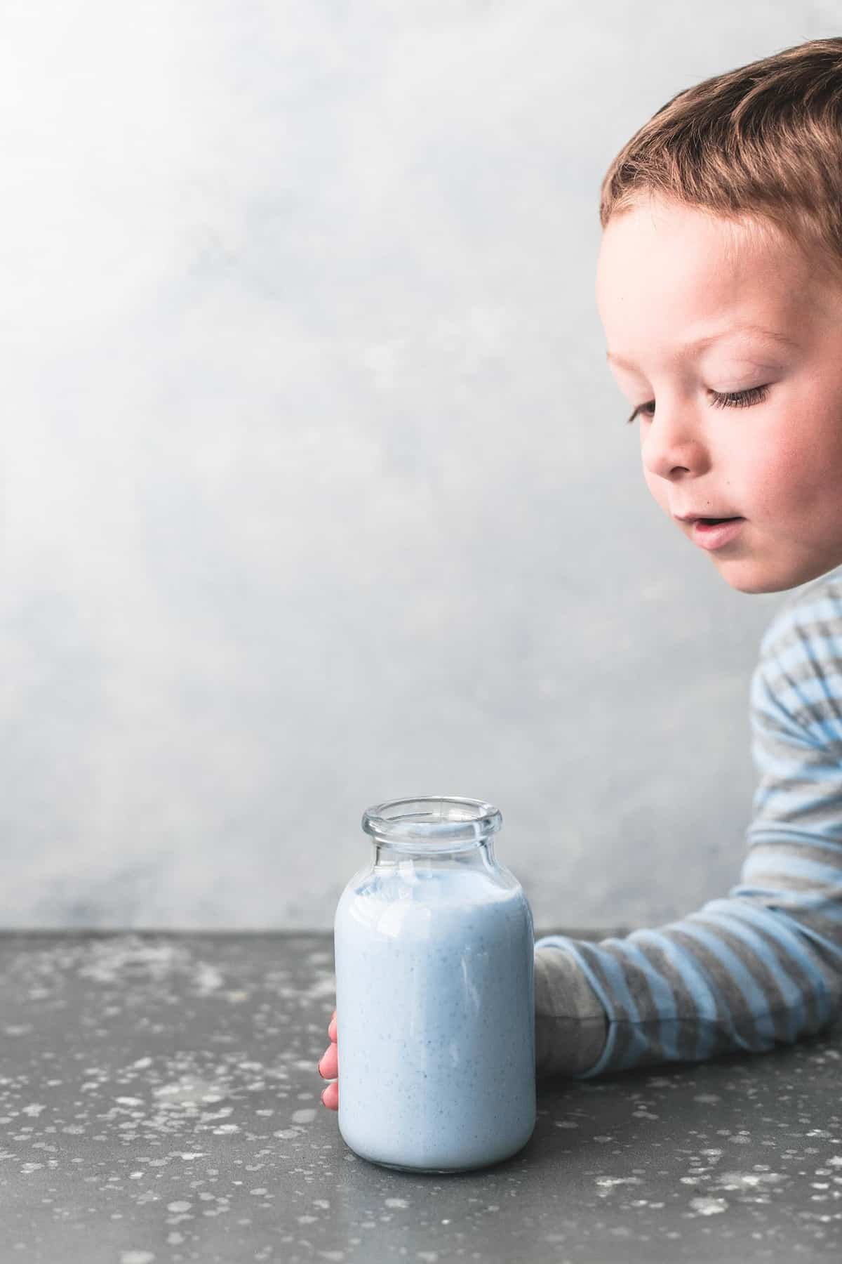 a kid picking up a glass jar of galaxy's edge blue milk (Disneyland Copycat).