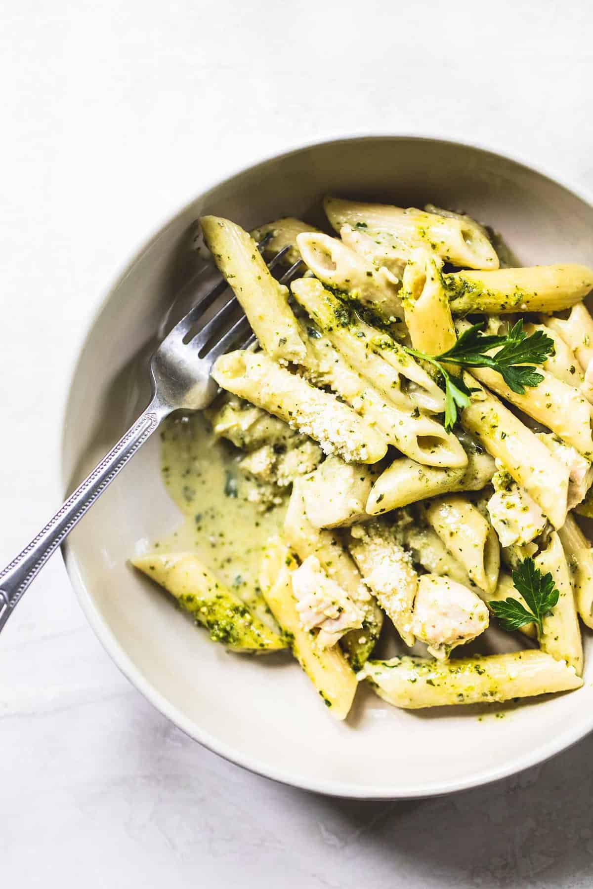 top eww of creamy pesto chicken pasta with a fork in a bowl.