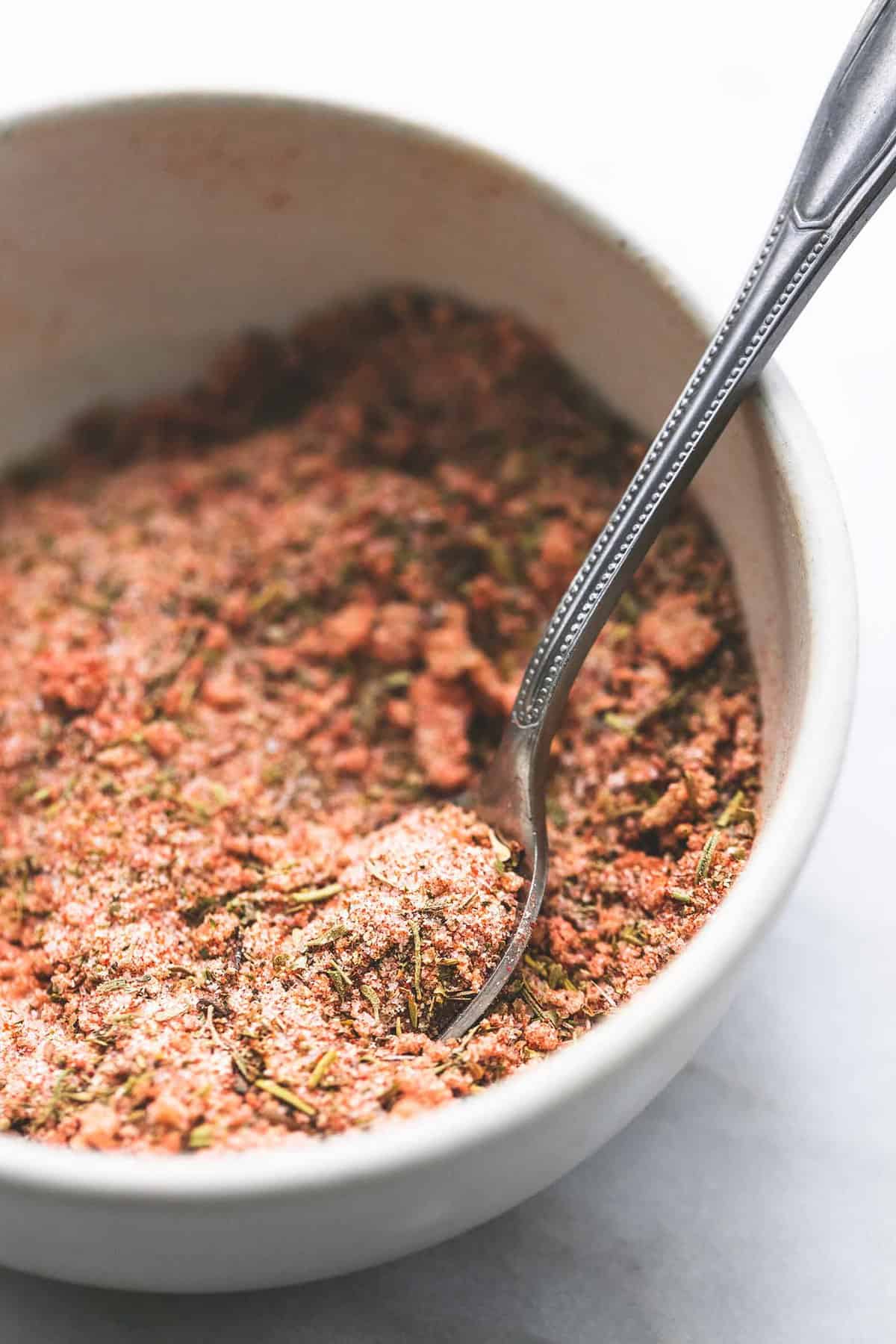 close up of grilled chicken dry rub with a spoon in a bowl.