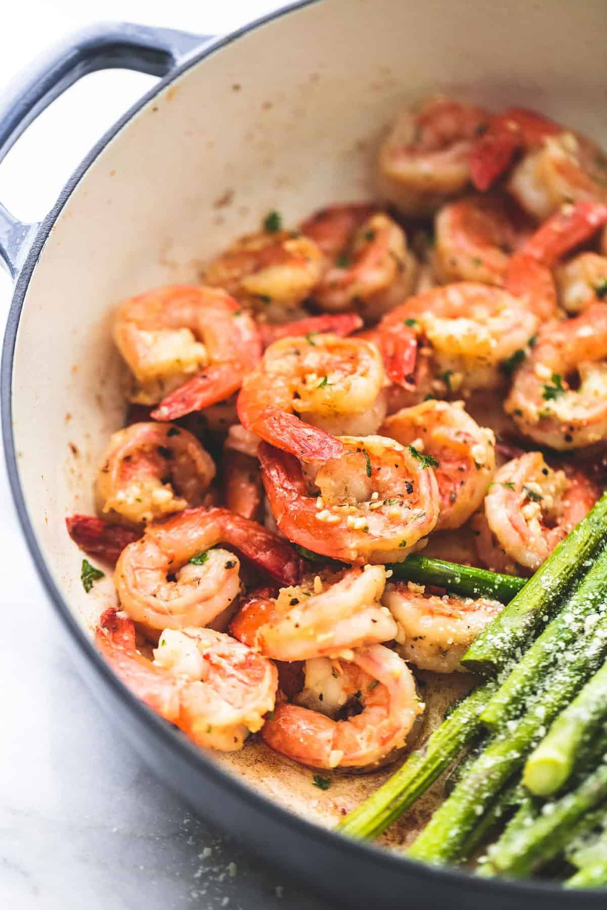 close up of shrimp in a pan with asparagus on the side.