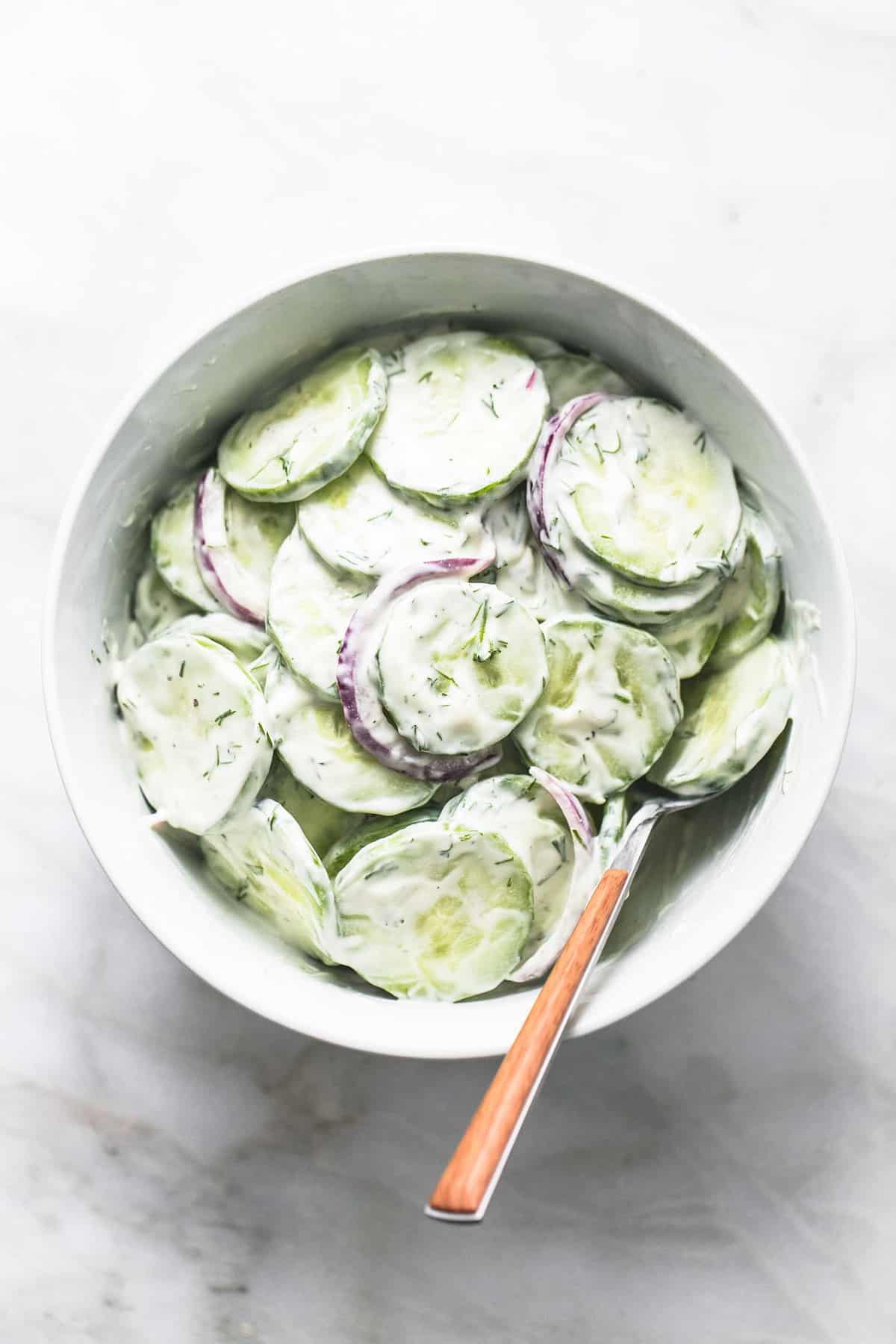 top view of creamy cucumber salad with a fork in a bowl.