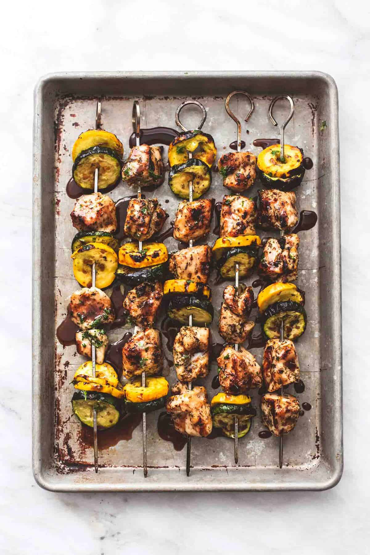 top view of balsamic chicken and veggie kabobs on a baking sheet.