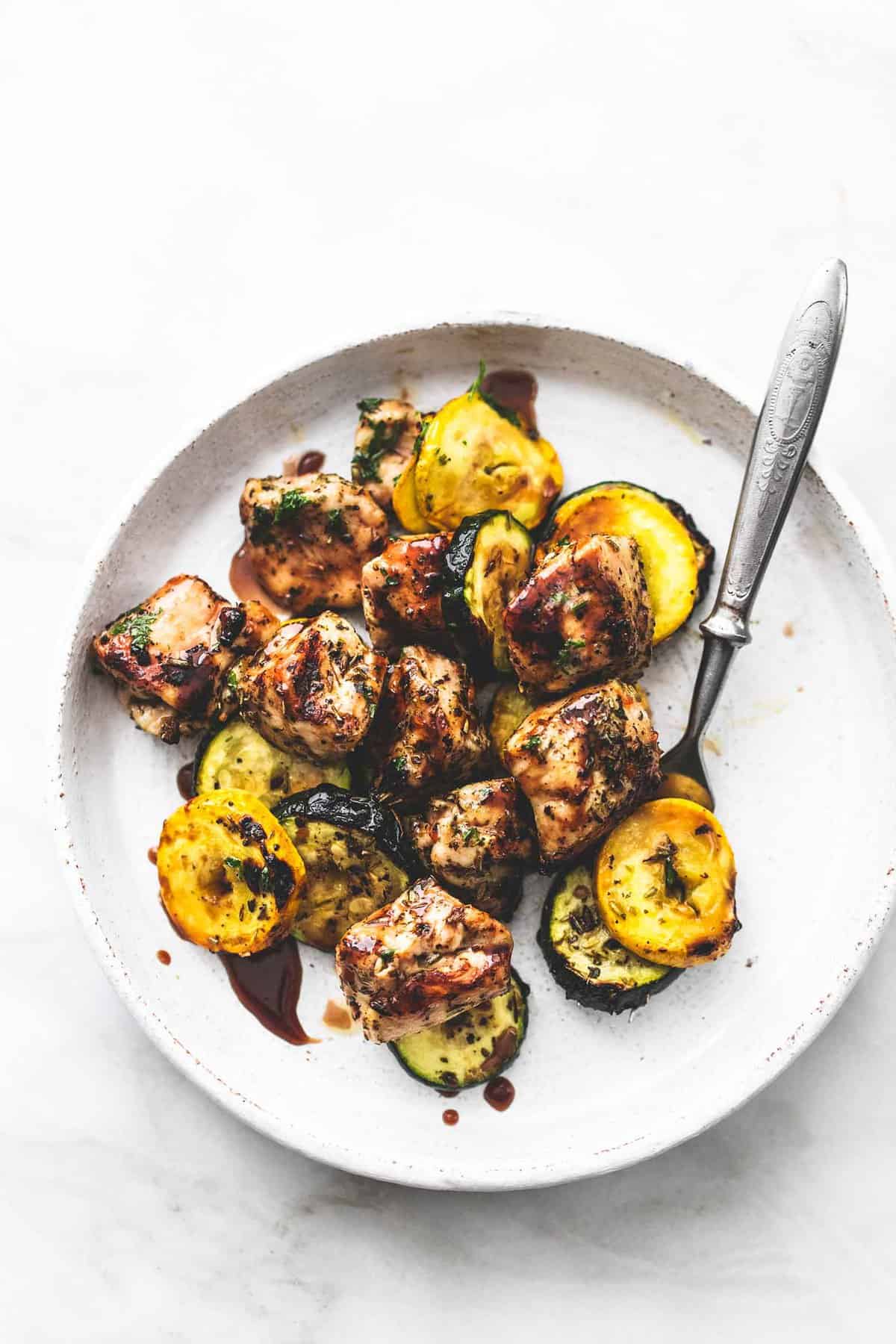 top view of deconstructed balsamic chicken and veggie kabobs with a bite on a fork on the side all on a plate.