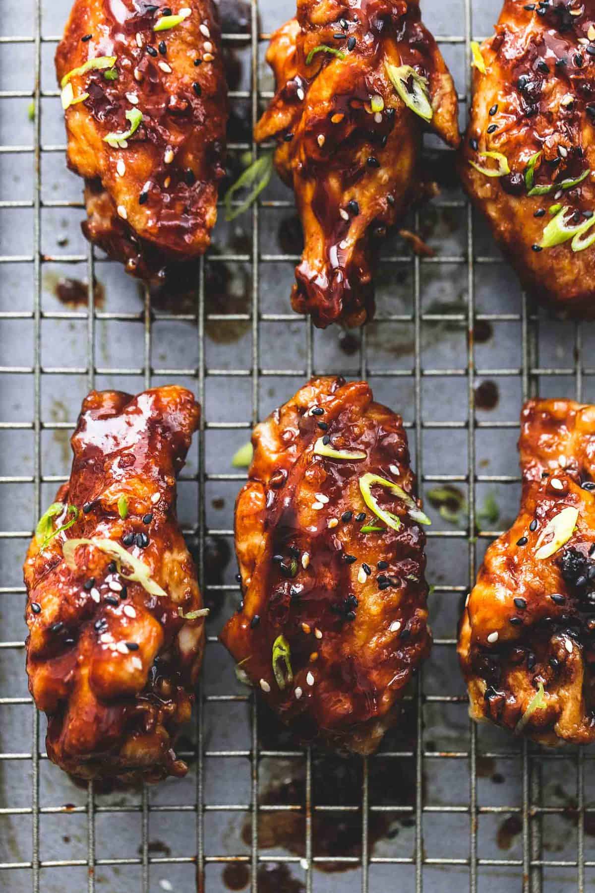 close up of spicy Korean bbq chicken wings on a cooling rack.