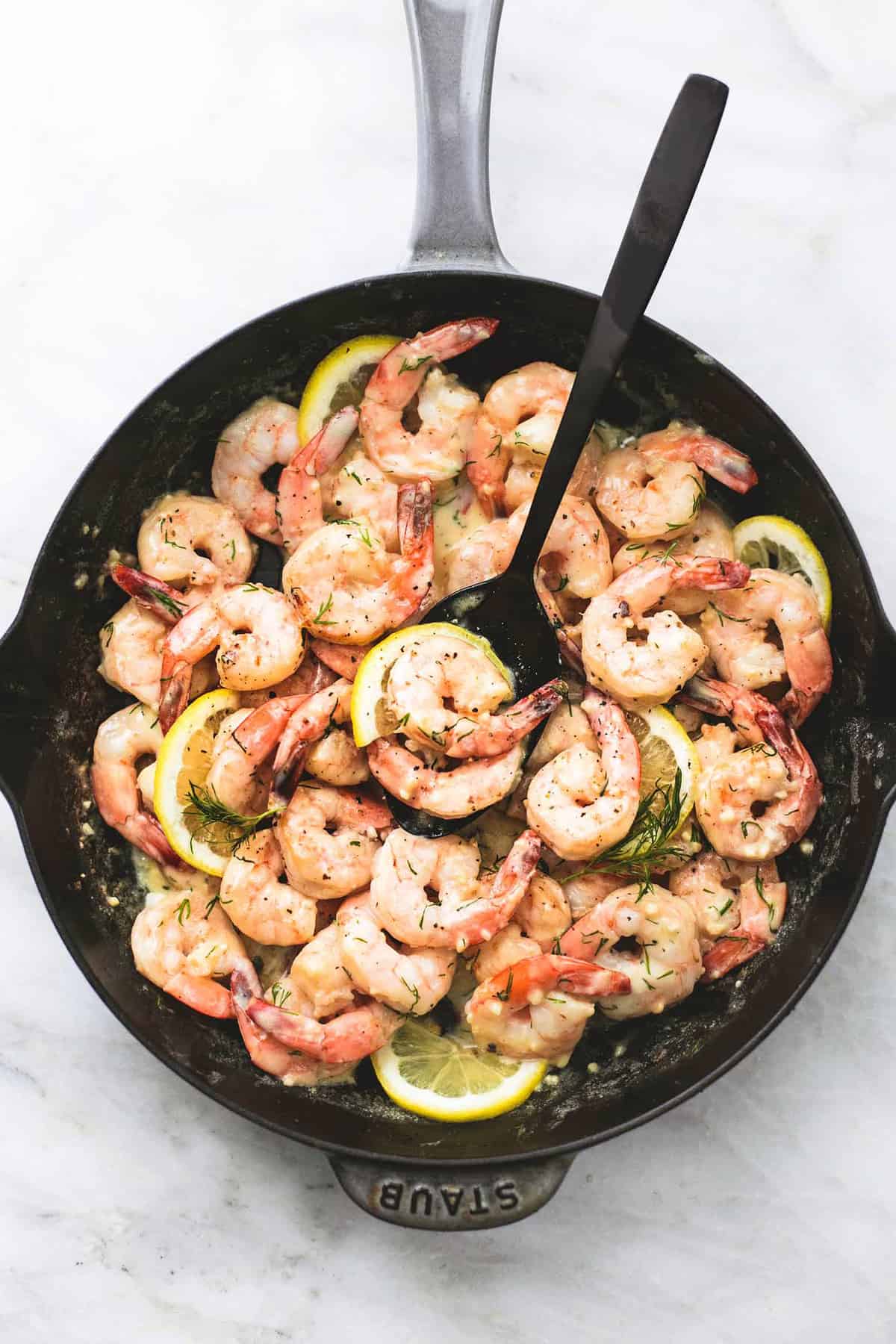top view of creamy lemon dill shrimp with a serving spoon in a pan.