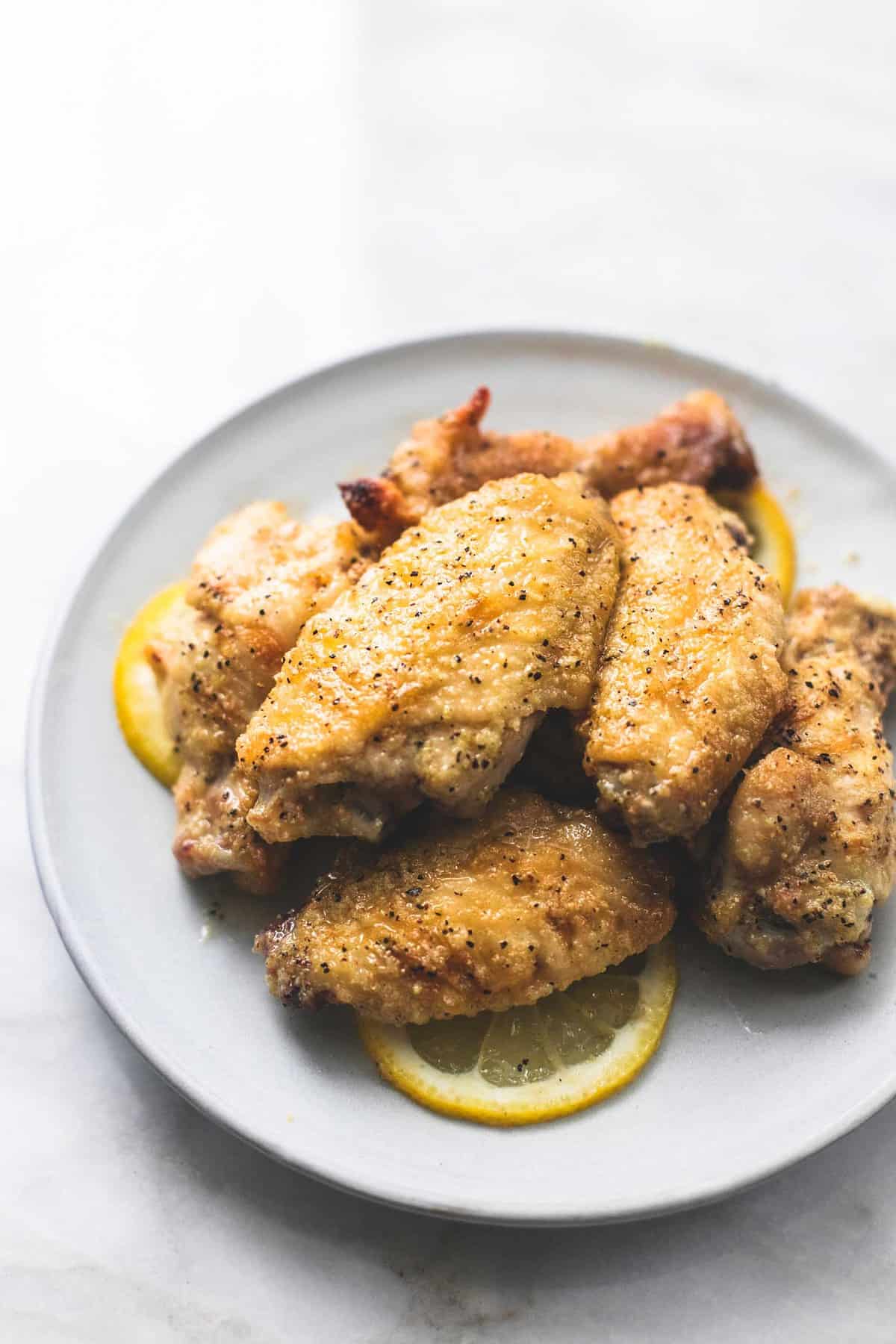 baked lemon pepper chicken wings and lemon wheels on a plate.