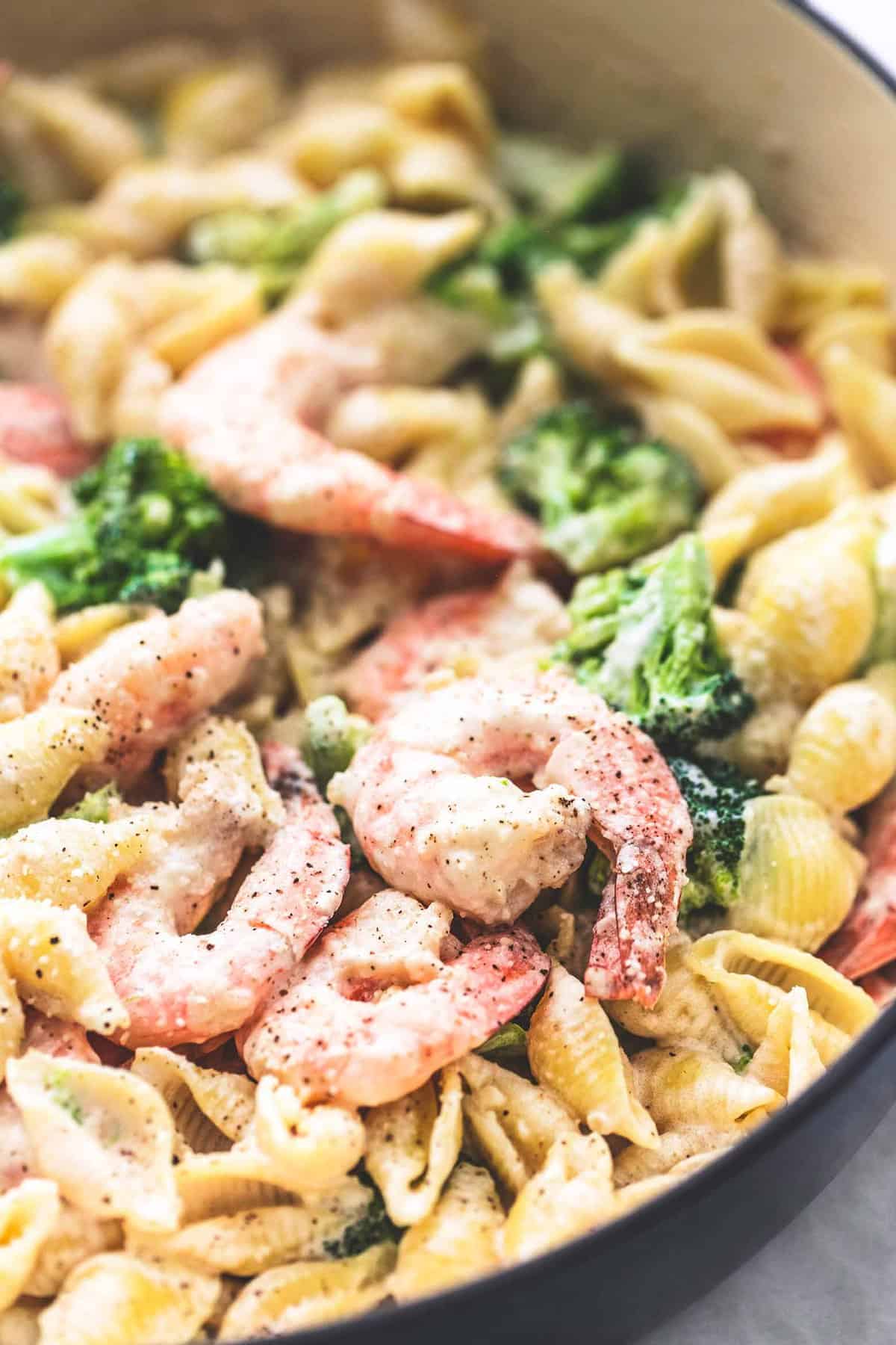 close up of shrimp and broccoli alfredo in a pan.