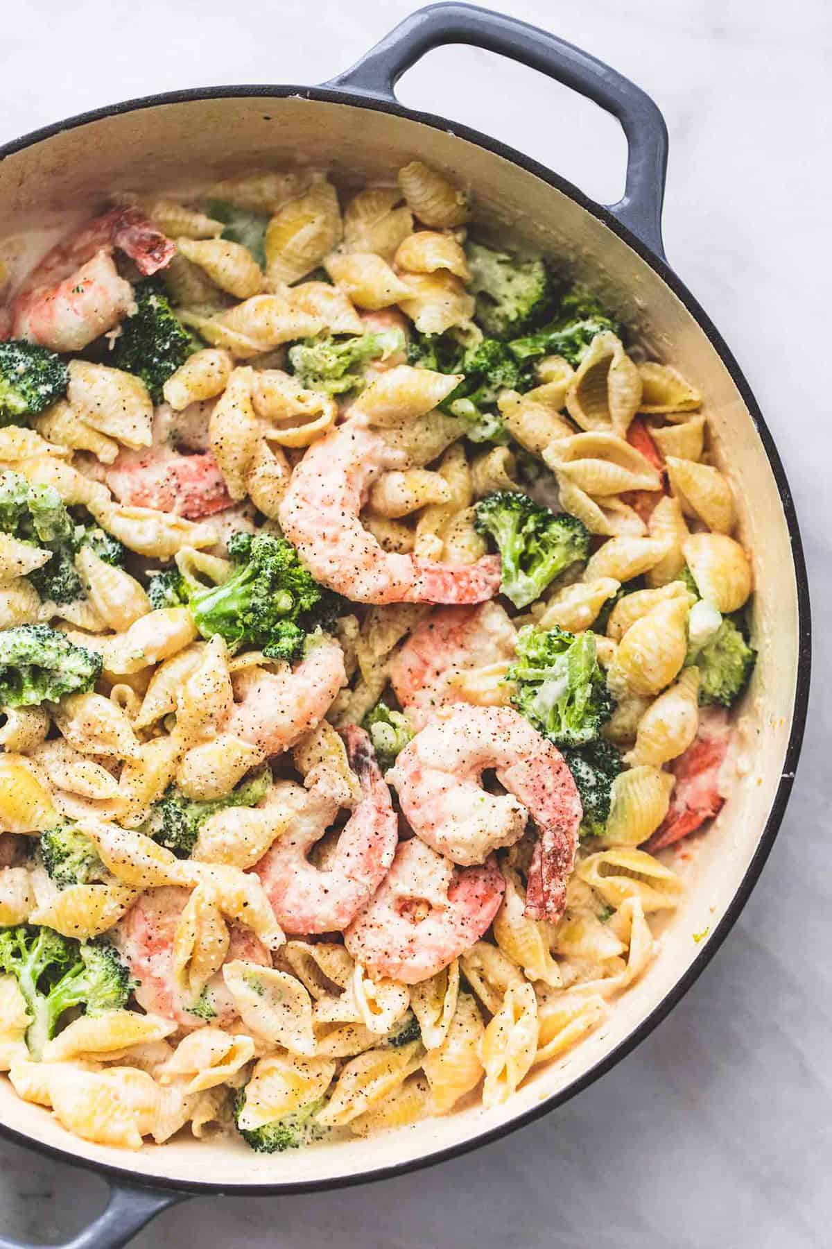 close up top view of shrimp and broccoli alfredo in a pan.