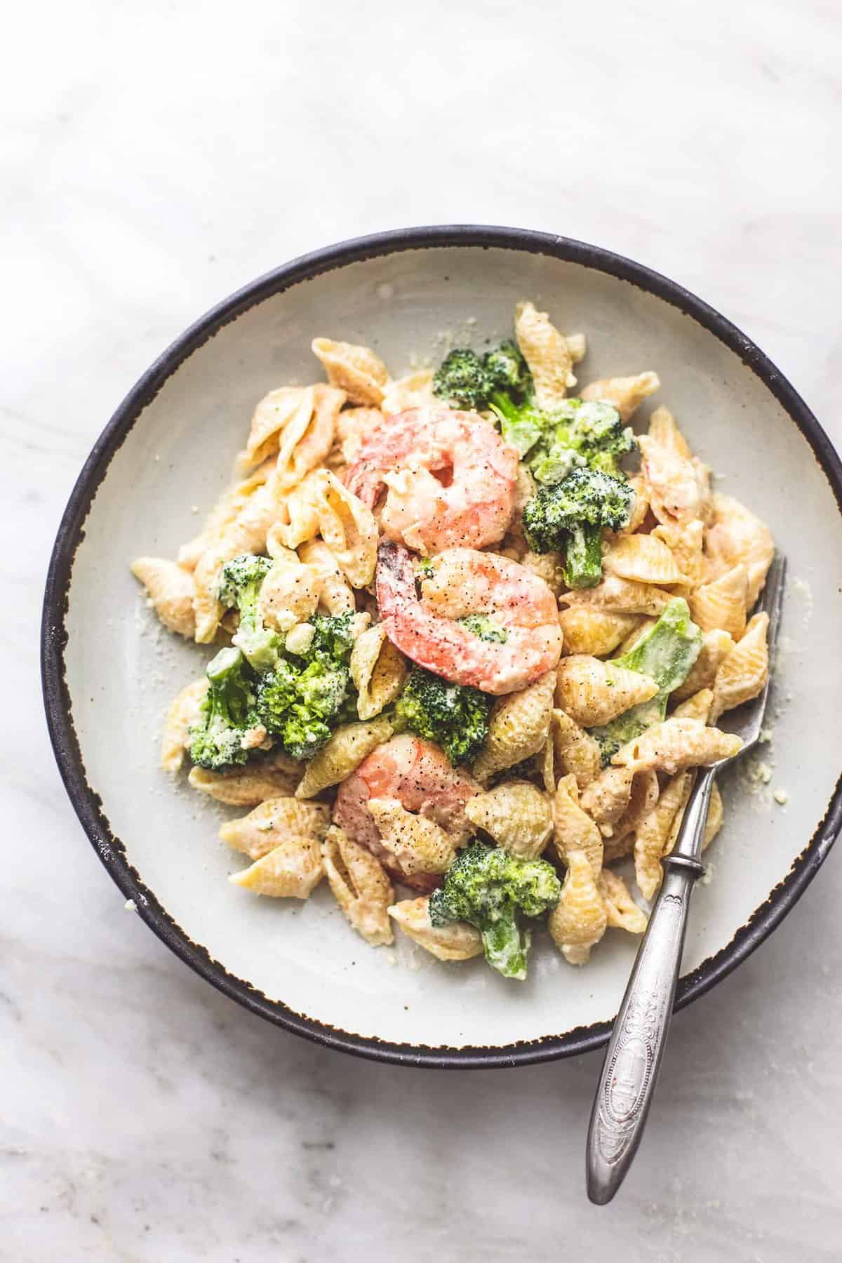 top view of shrimp and broccoli alfredo with a fork on a plate.