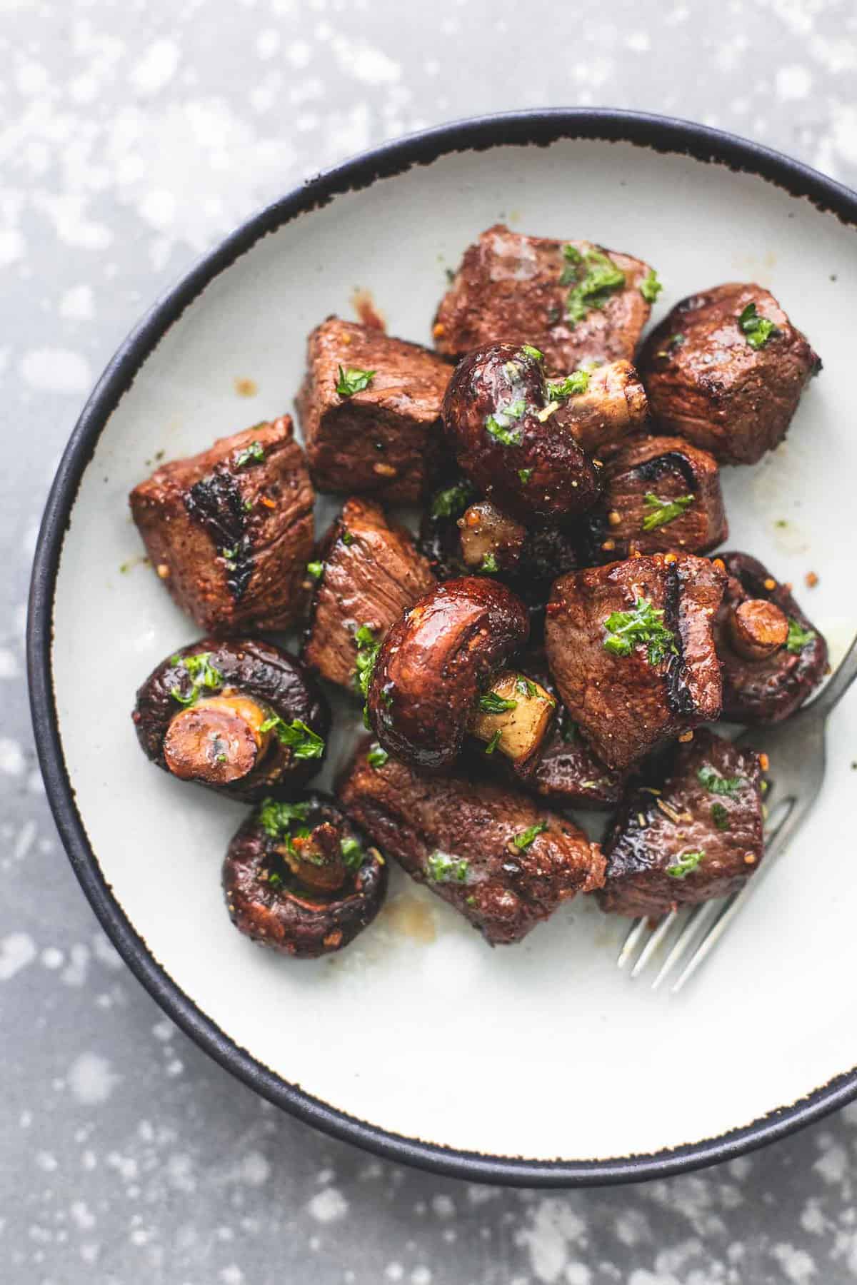 top view of deconstructed grilled steak and mushroom kabobs with a fork on a plate.