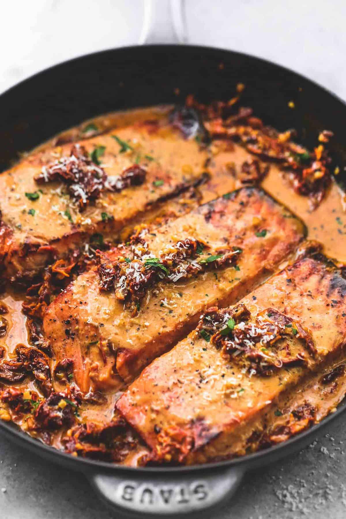 salmon in creamy sun dried tomato sauce in a pan.