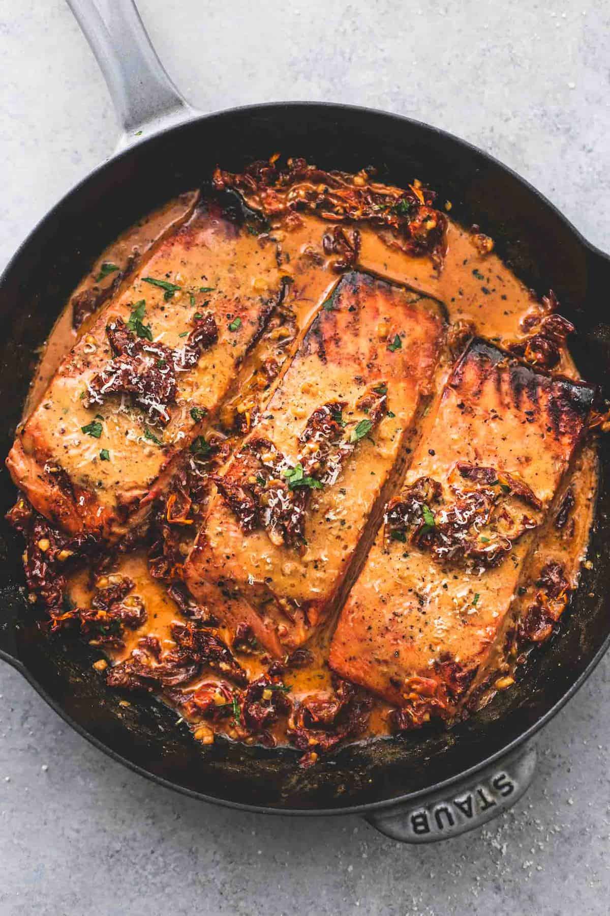 top view of salmon in creamy sun dried tomato sauce in a pan.