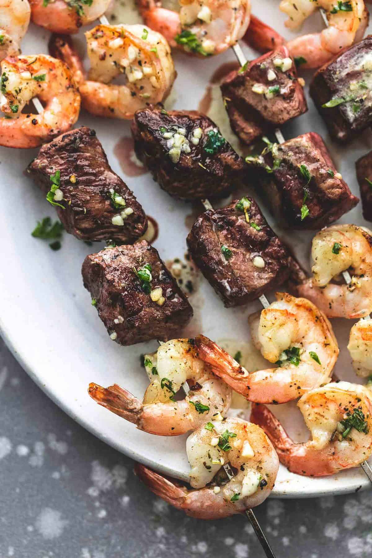 close up top view of garlic butter surf and turf kabobs on a plate.