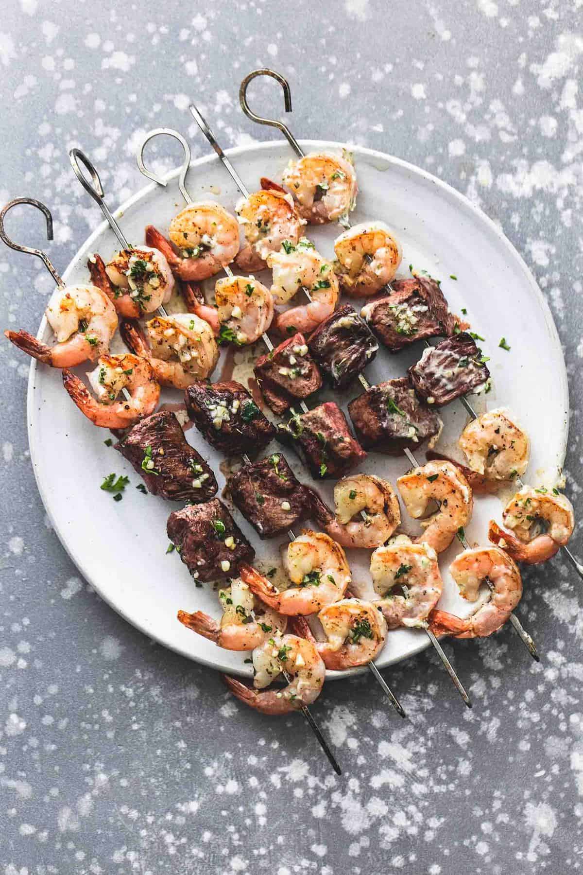 top view of garlic butter surf and turf kabobs on a plate.