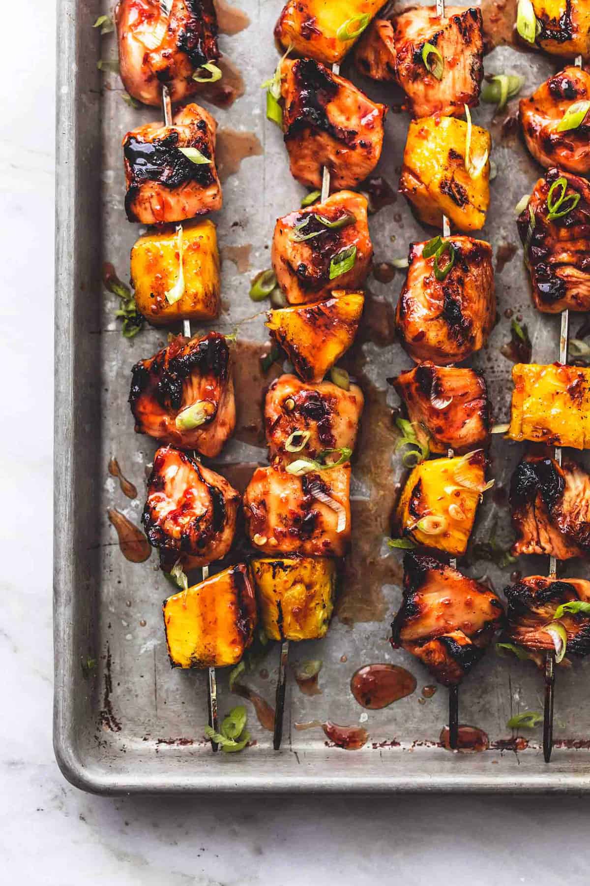 close up top view of grilled sweet and spicy Thai chicken kabobs on a baking sheet.