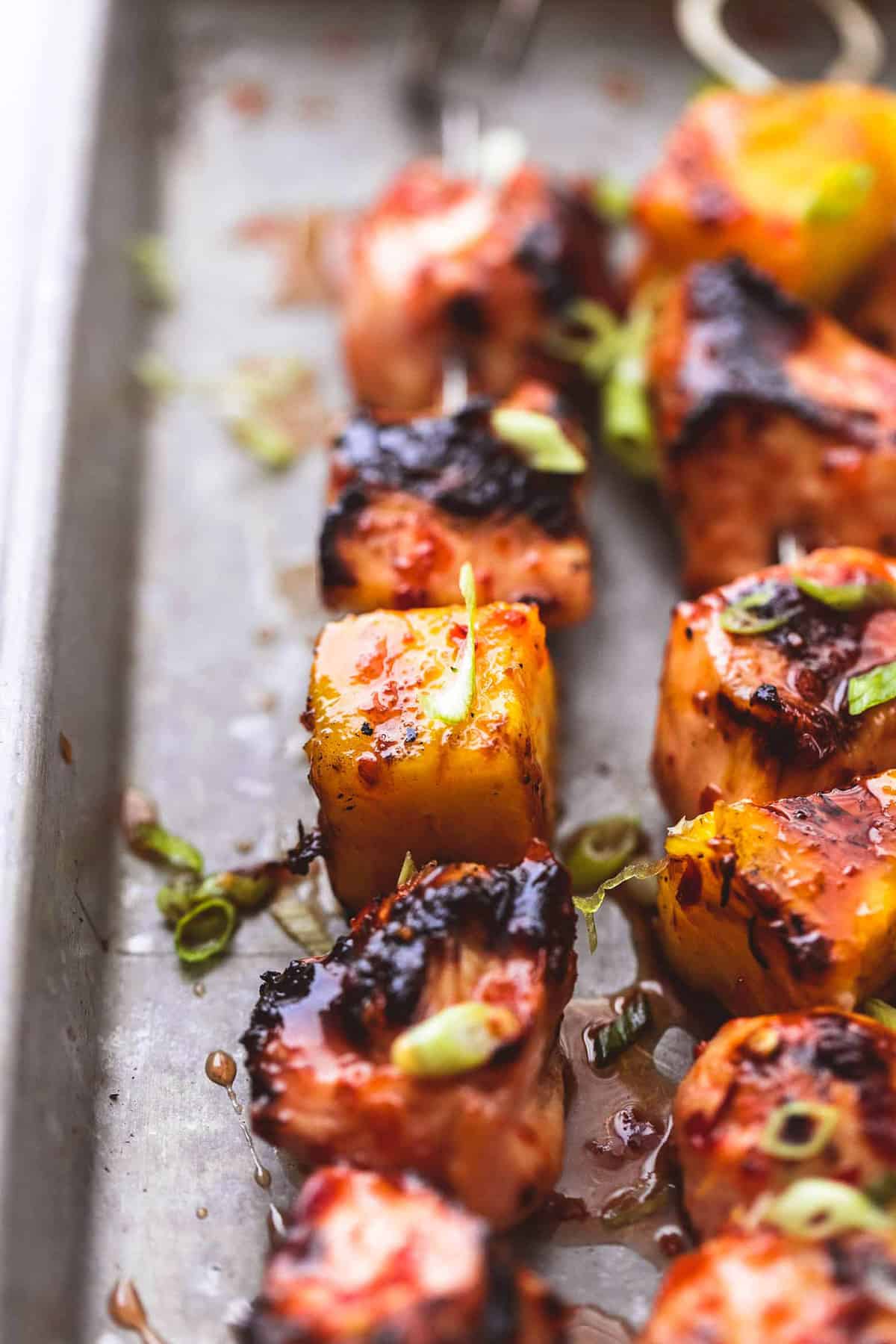 close up of grilled sweet and spicy Thai chicken kabobs on a baking sheet.