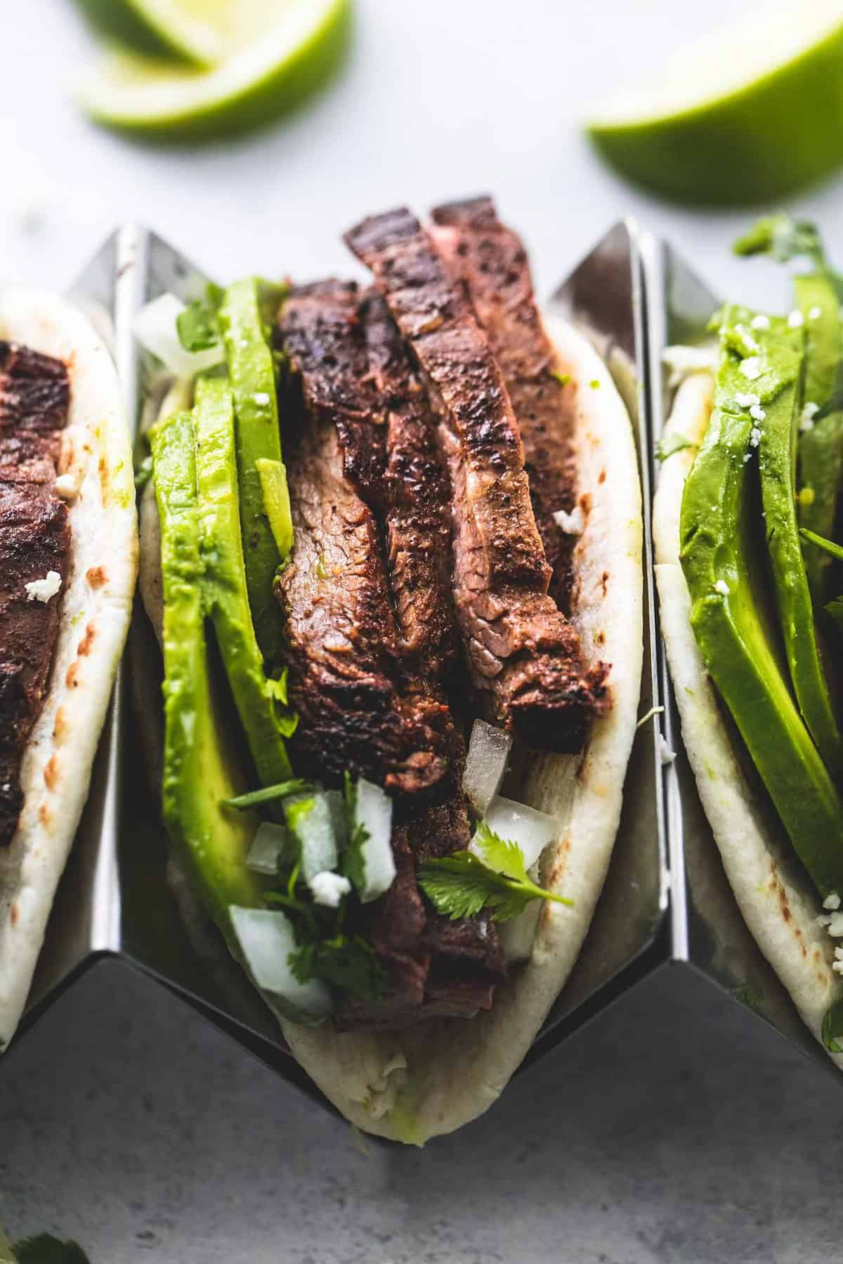 close up of a flank steak taco on a taco rack with more tacos on the sides.