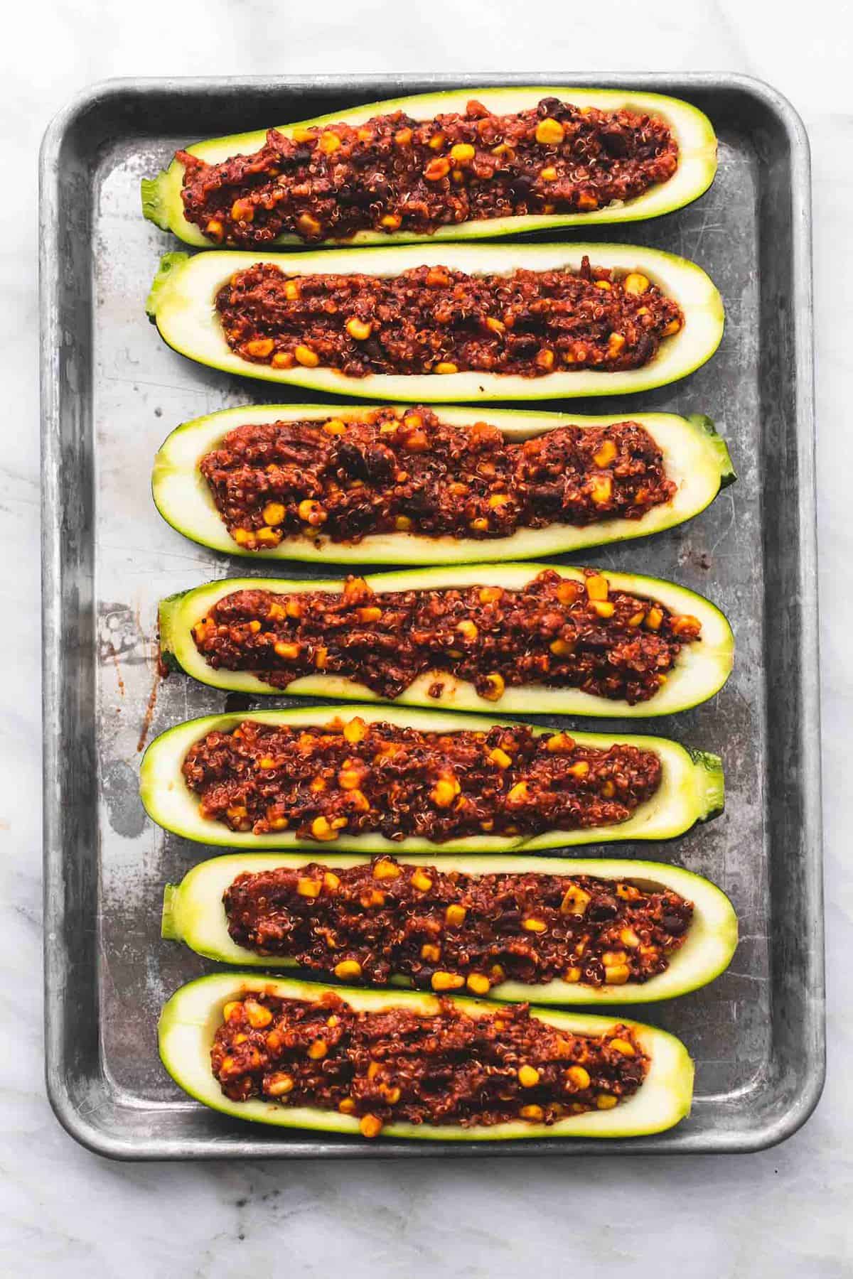 top view of enchilada quinoa stuffed zucchini boats without cheese and toppings on them on a baking sheet.