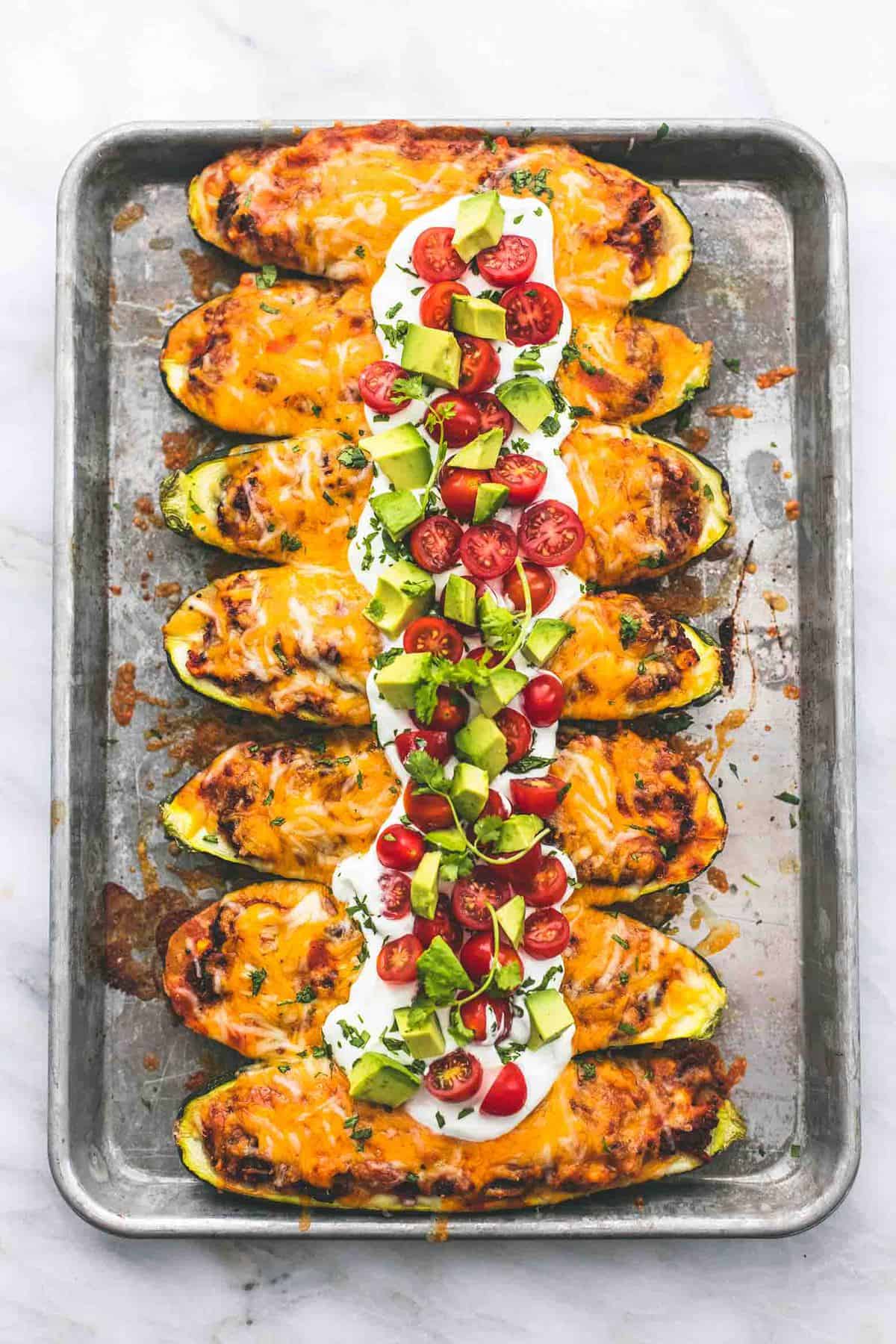 top view of enchilada quinoa stuffed zucchini boats on a baking sheet.