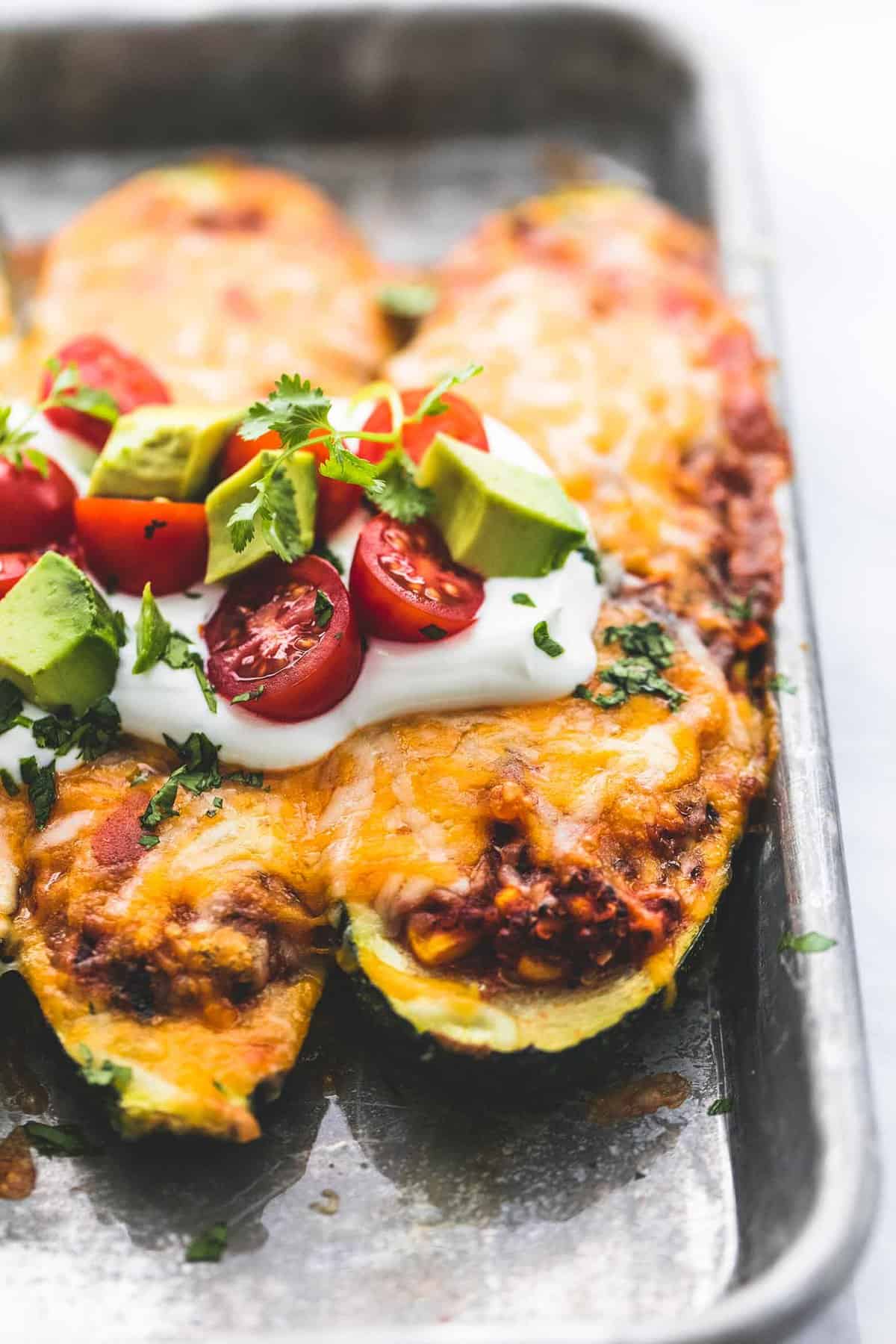 close up of enchilada quinoa stuffed zucchini boats on a baking sheet.