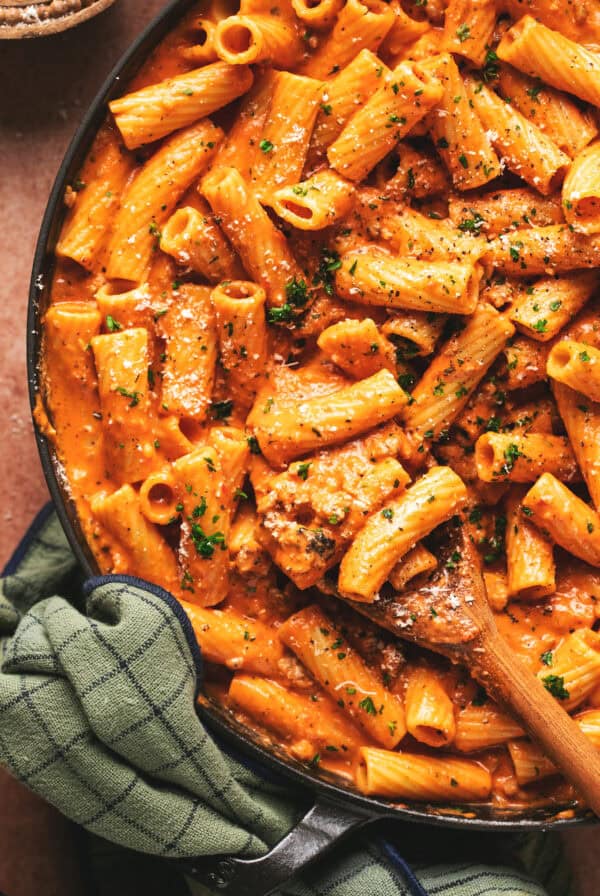 Overhead of pasta with creamy roasted red pepper sauce in a skillet.