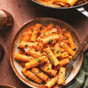Overhead of pasta with creamy roasted red pepper sauce and a fork on a plate.