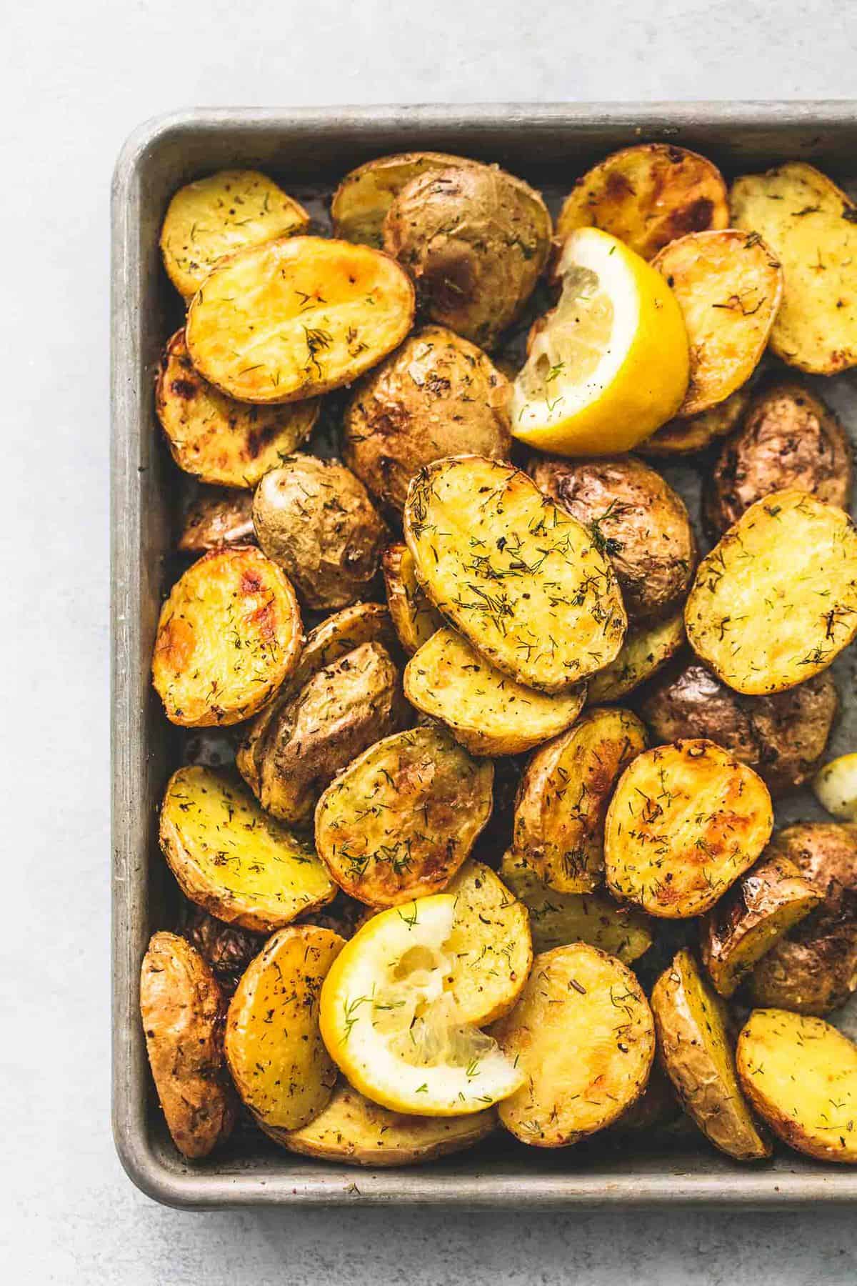 close up of oven roasted dill potatoes with lemon slices on a baking sheet.