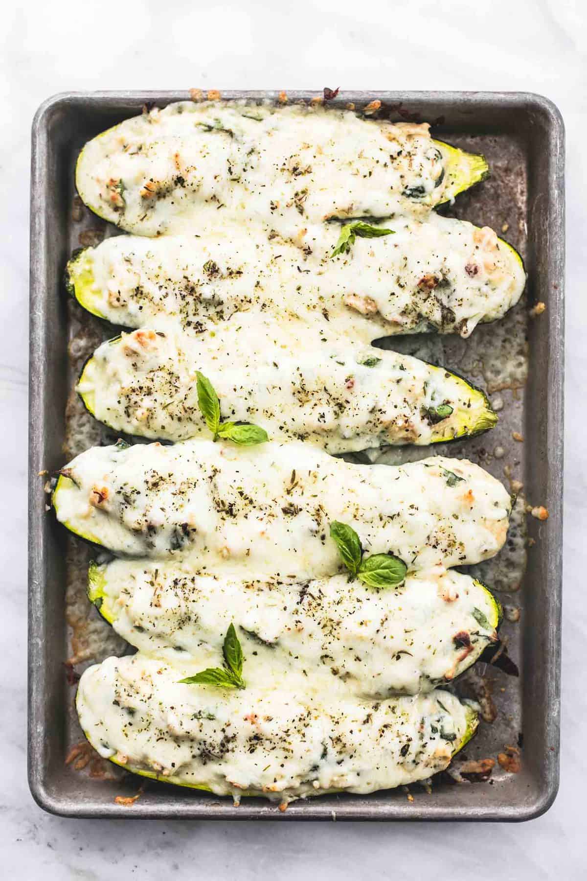 top view of white chicken lasagna stuffed zucchini boats on a baking sheet.