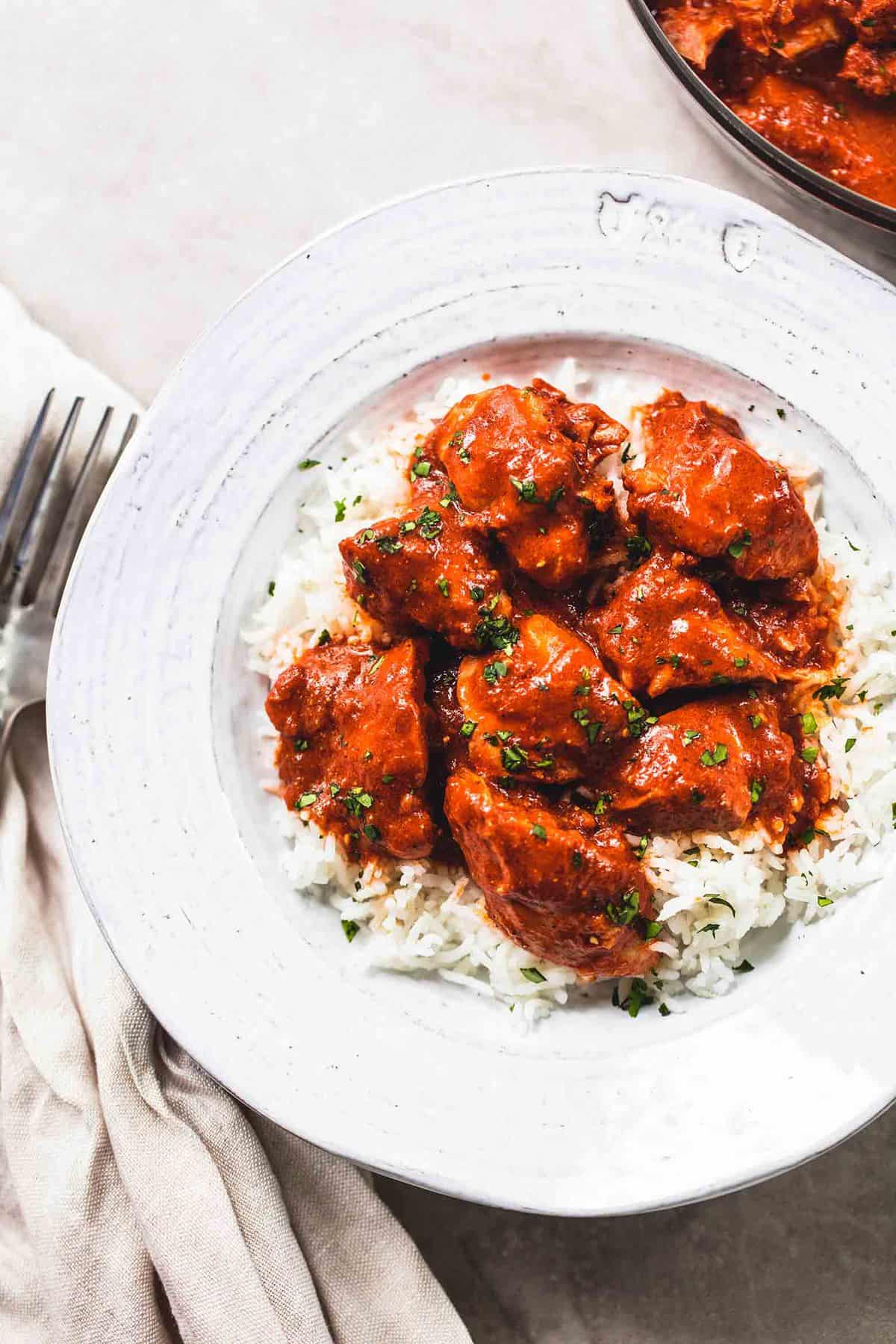 top view of instant pot chicken tikka masala on rice in a bowl with a fork on the side.