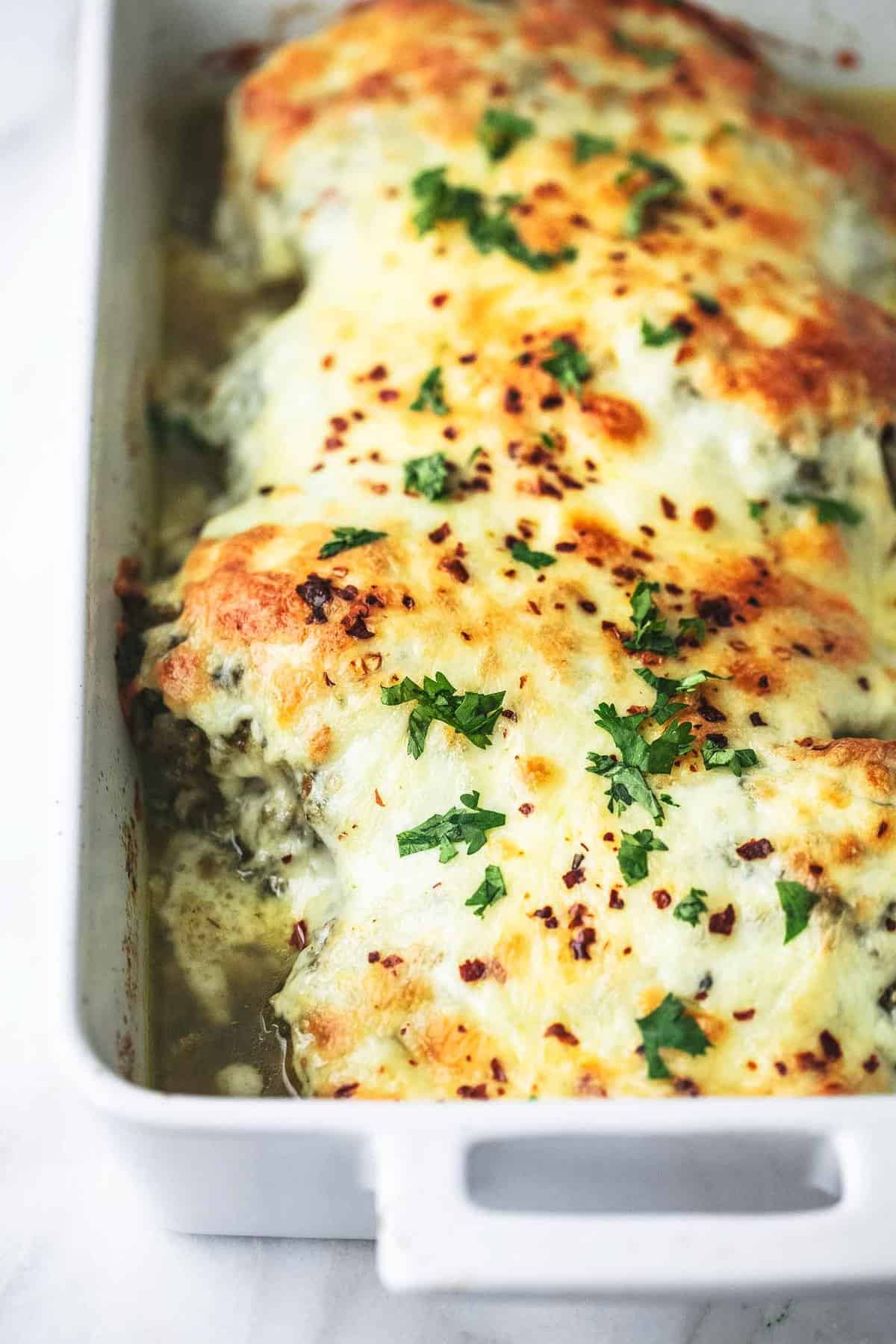 close up of baked salsa verde chicken in a baking pan.
